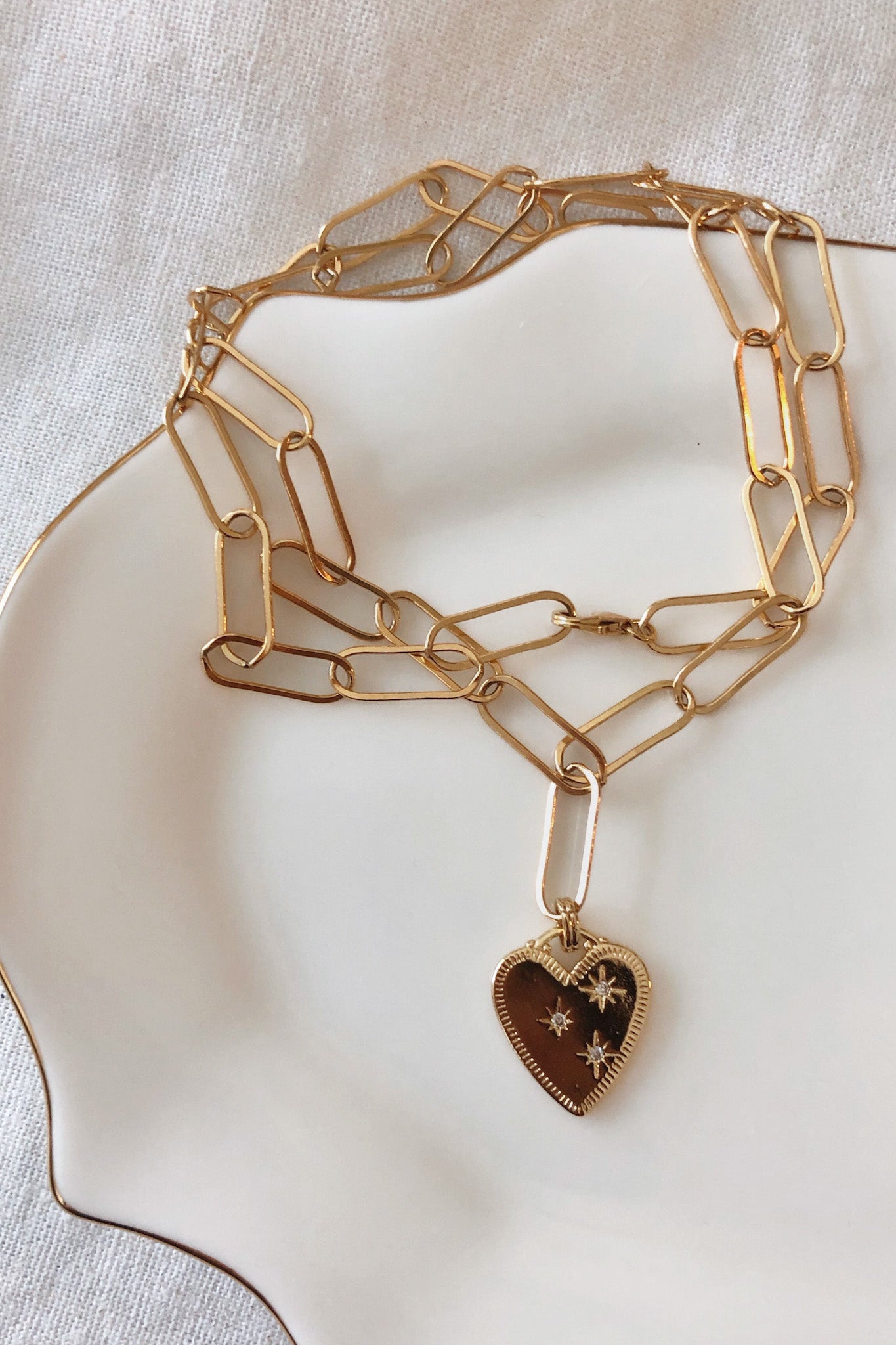 Gold chain necklace with a heart-shaped pendant on a light background
