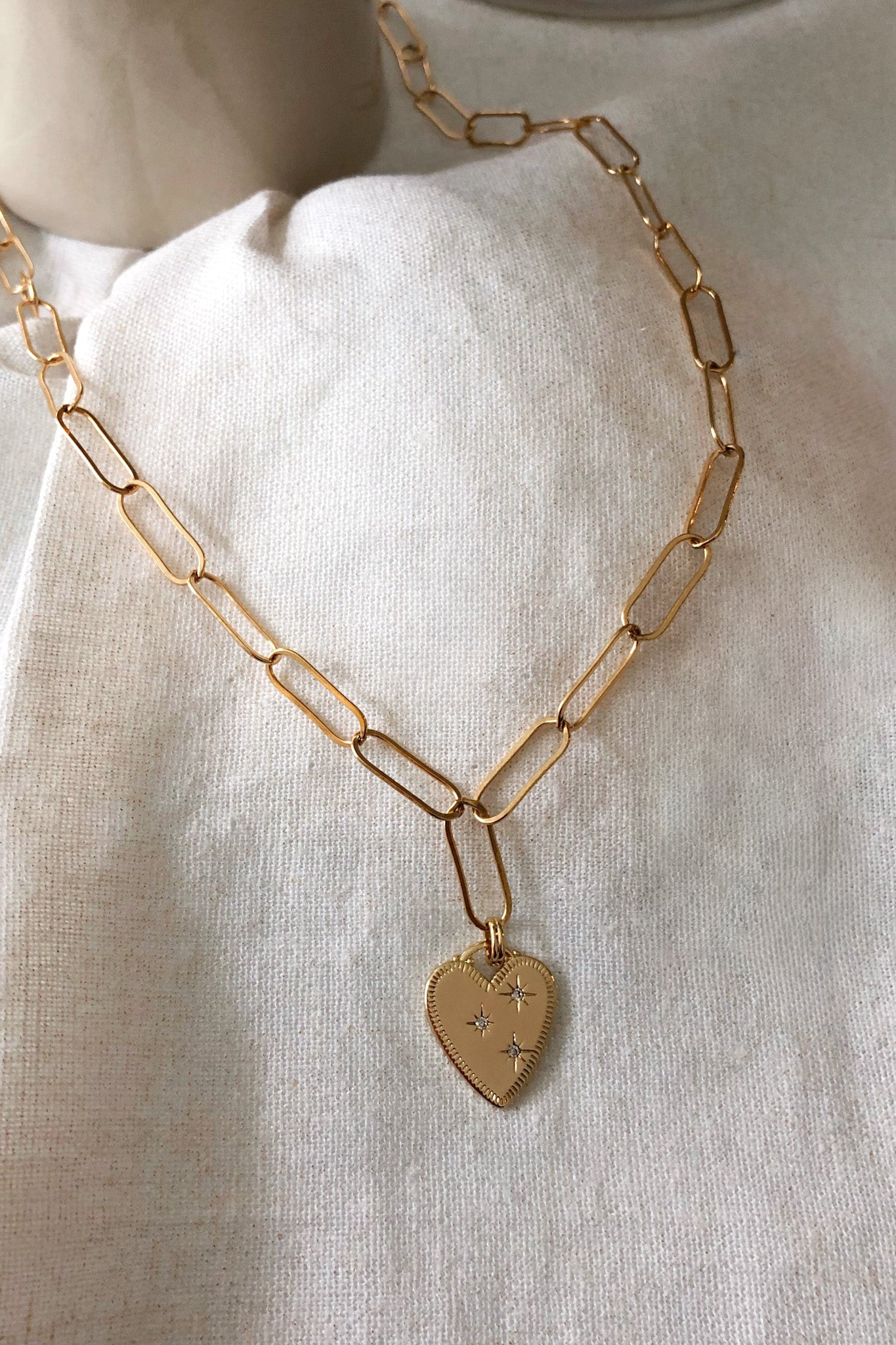 Gold chain necklace with a heart pendant on a white background