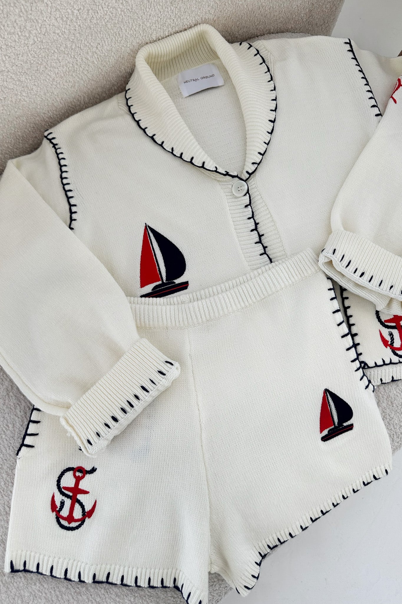 White sweater with sailboat and anchor designs on a neutral background