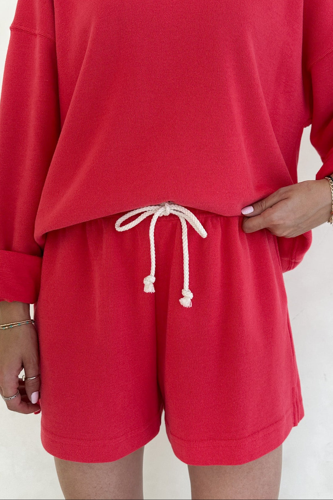 Person wearing a red sweatshirt and shorts set on a white background