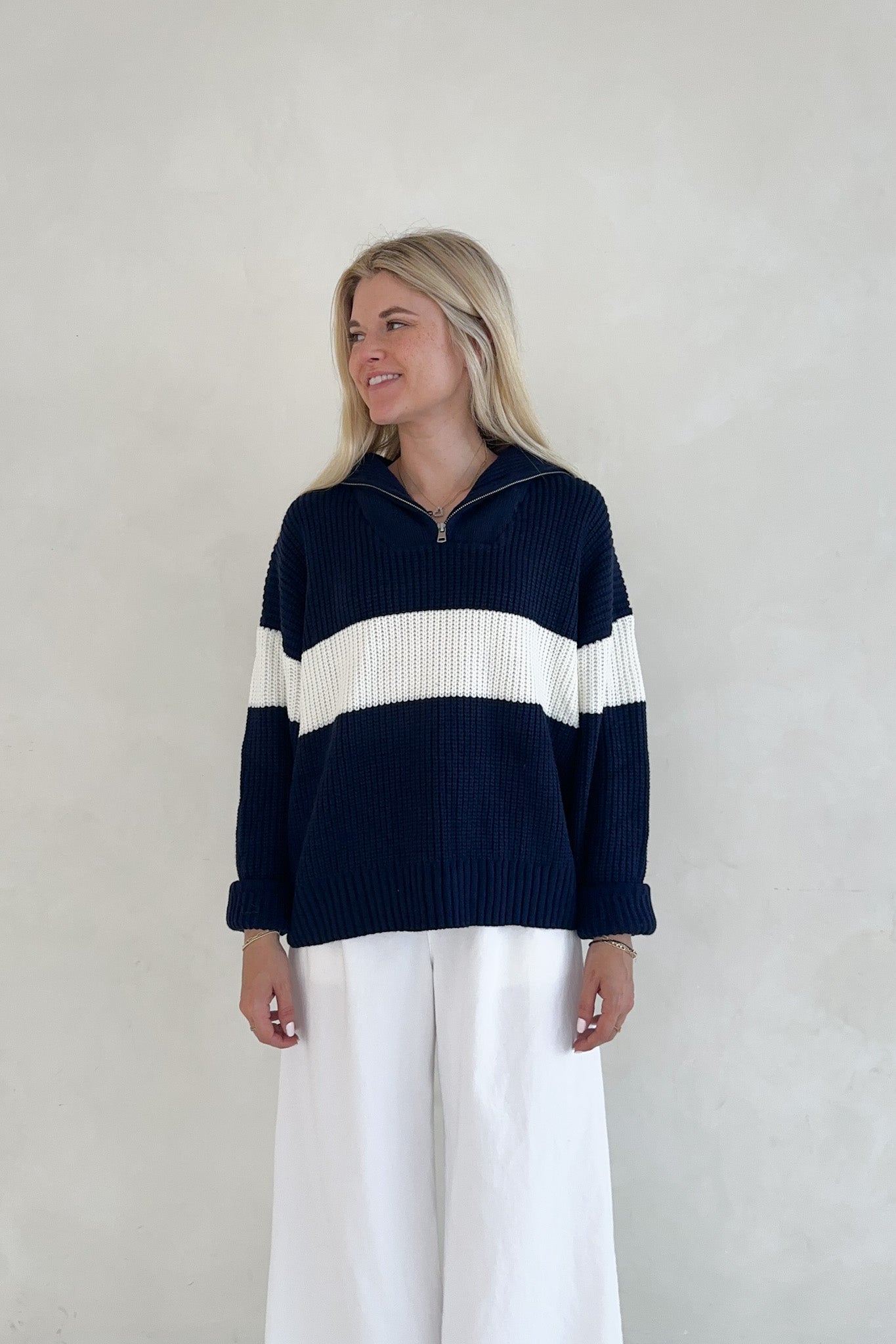 Woman wearing a navy and white striped sweater against a plain background