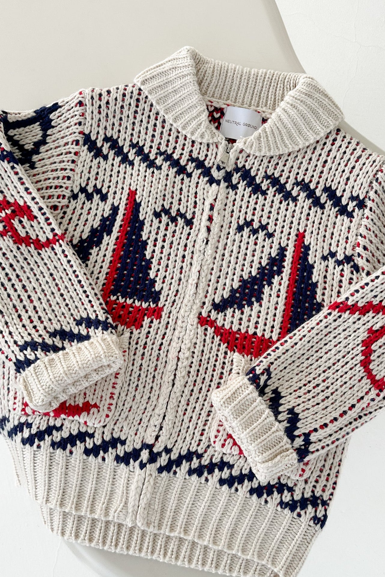 Knitted sweater with sailboat pattern on a mannequin against a white background