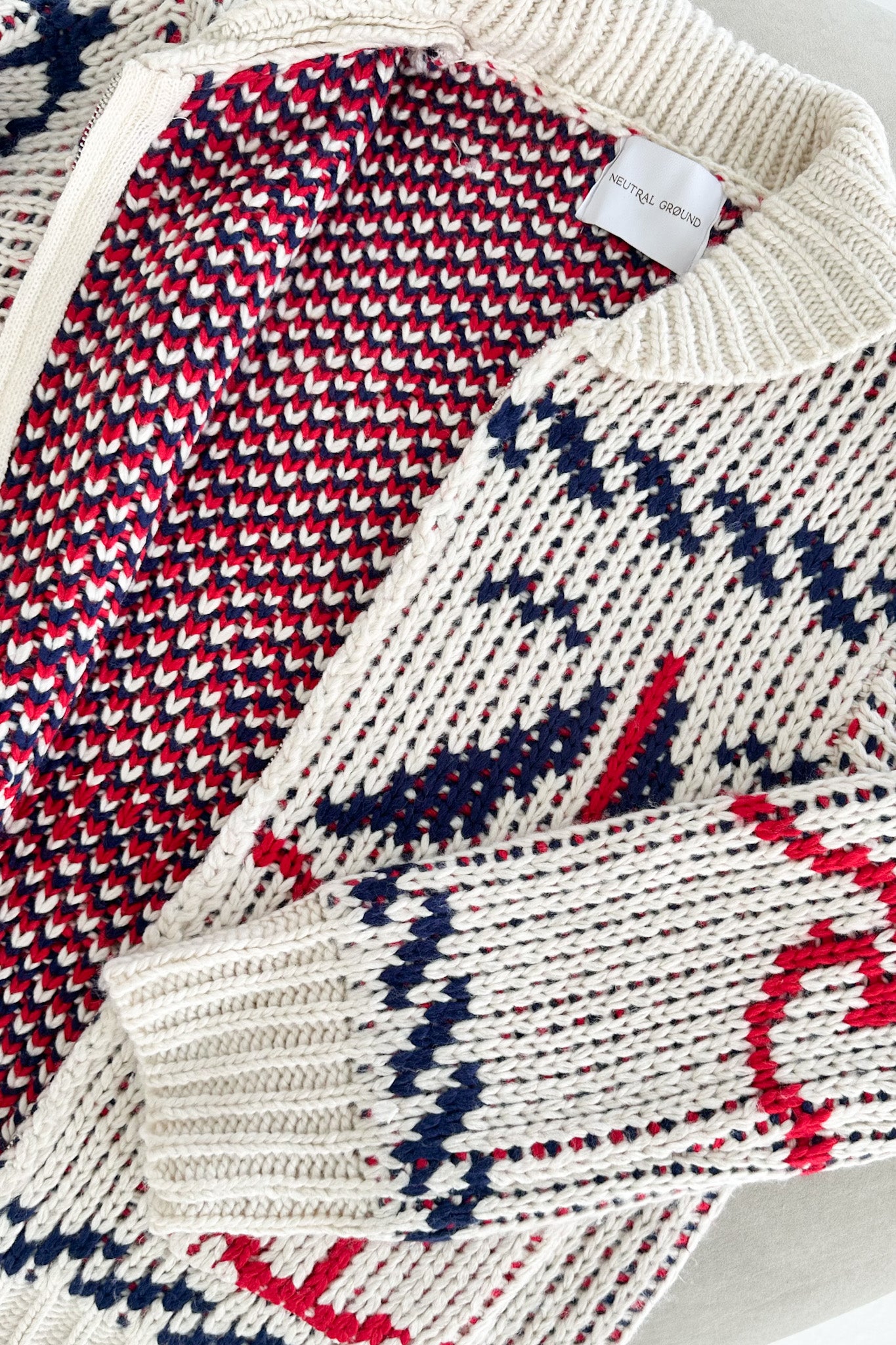 Close-up of a patterned sweater with a brand label on a light background