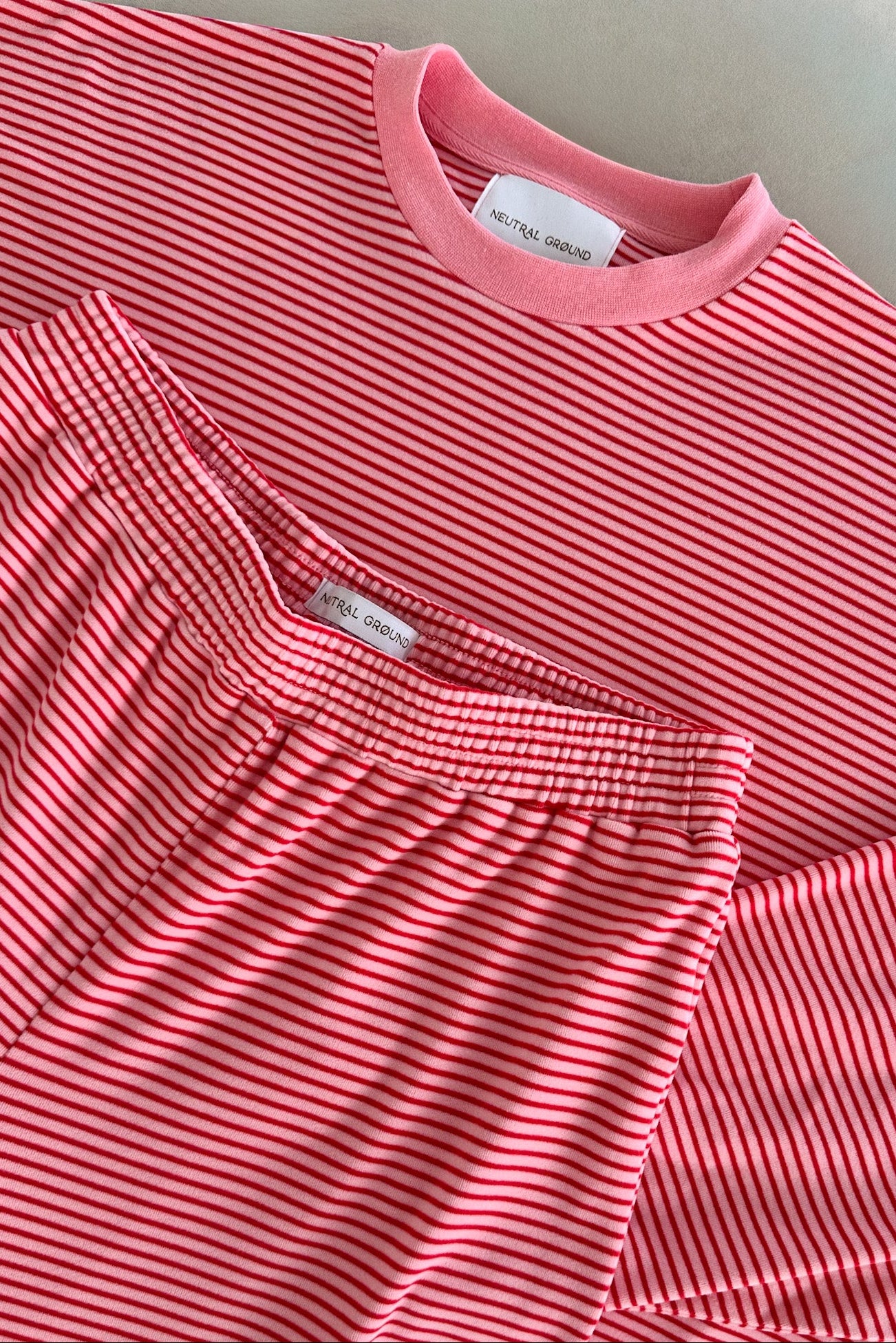 Pink striped shirt with a brand label on a light gray background