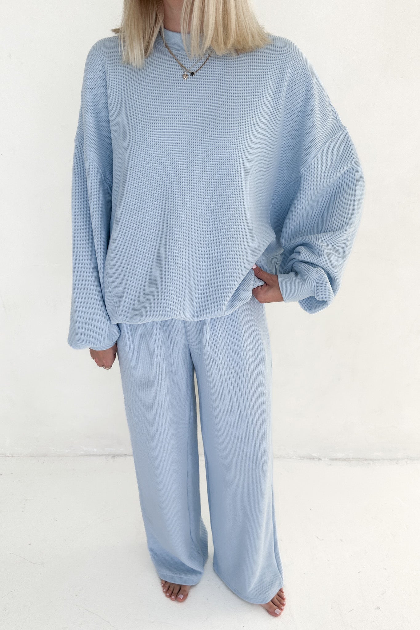 Person wearing a light blue outfit on a white background