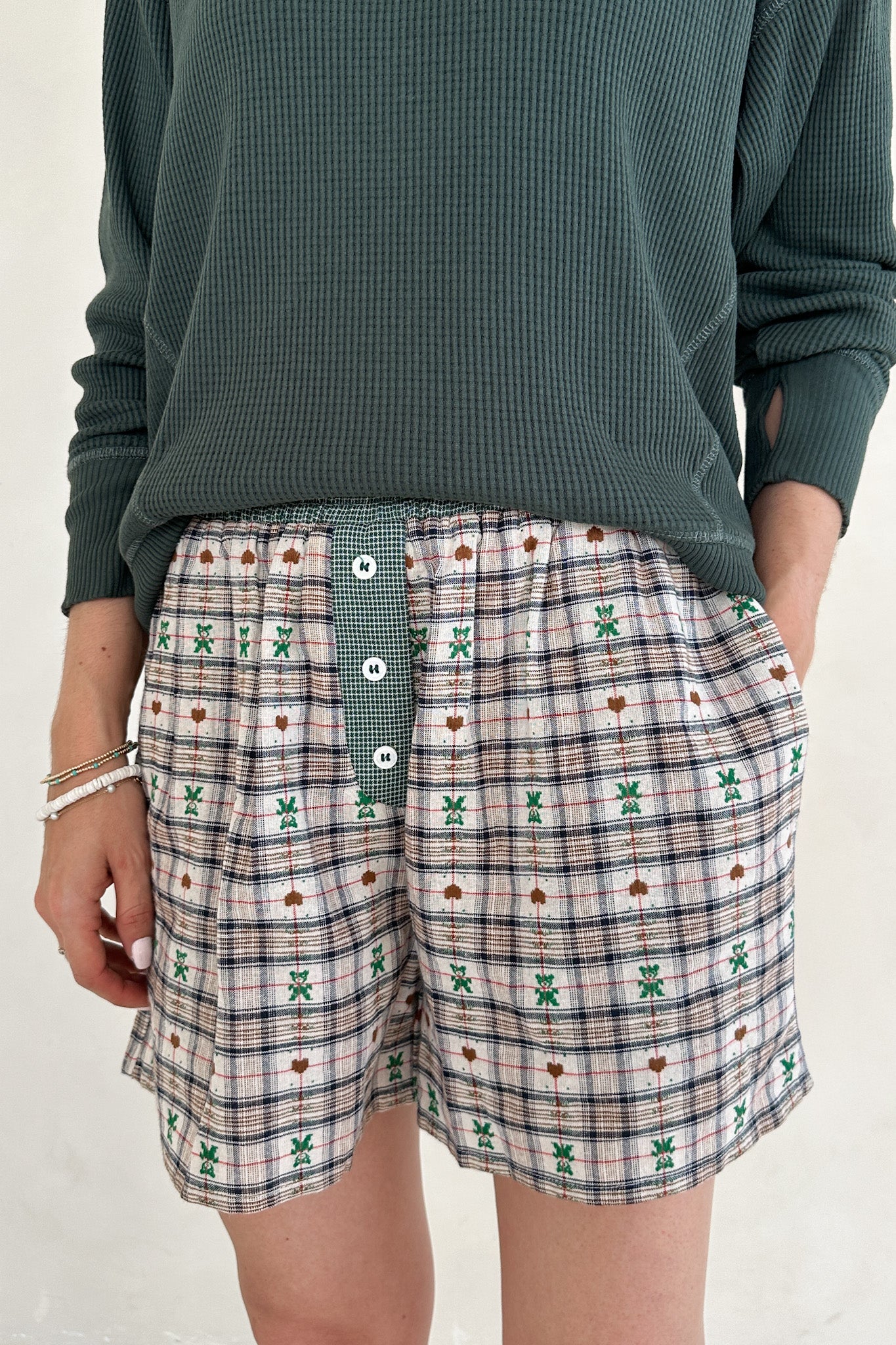 Person wearing plaid shorts with a green top on a plain background