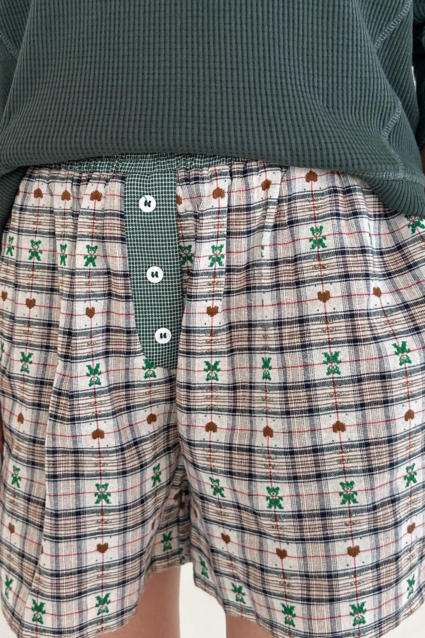 Plaid shorts with green patterns on a plain background