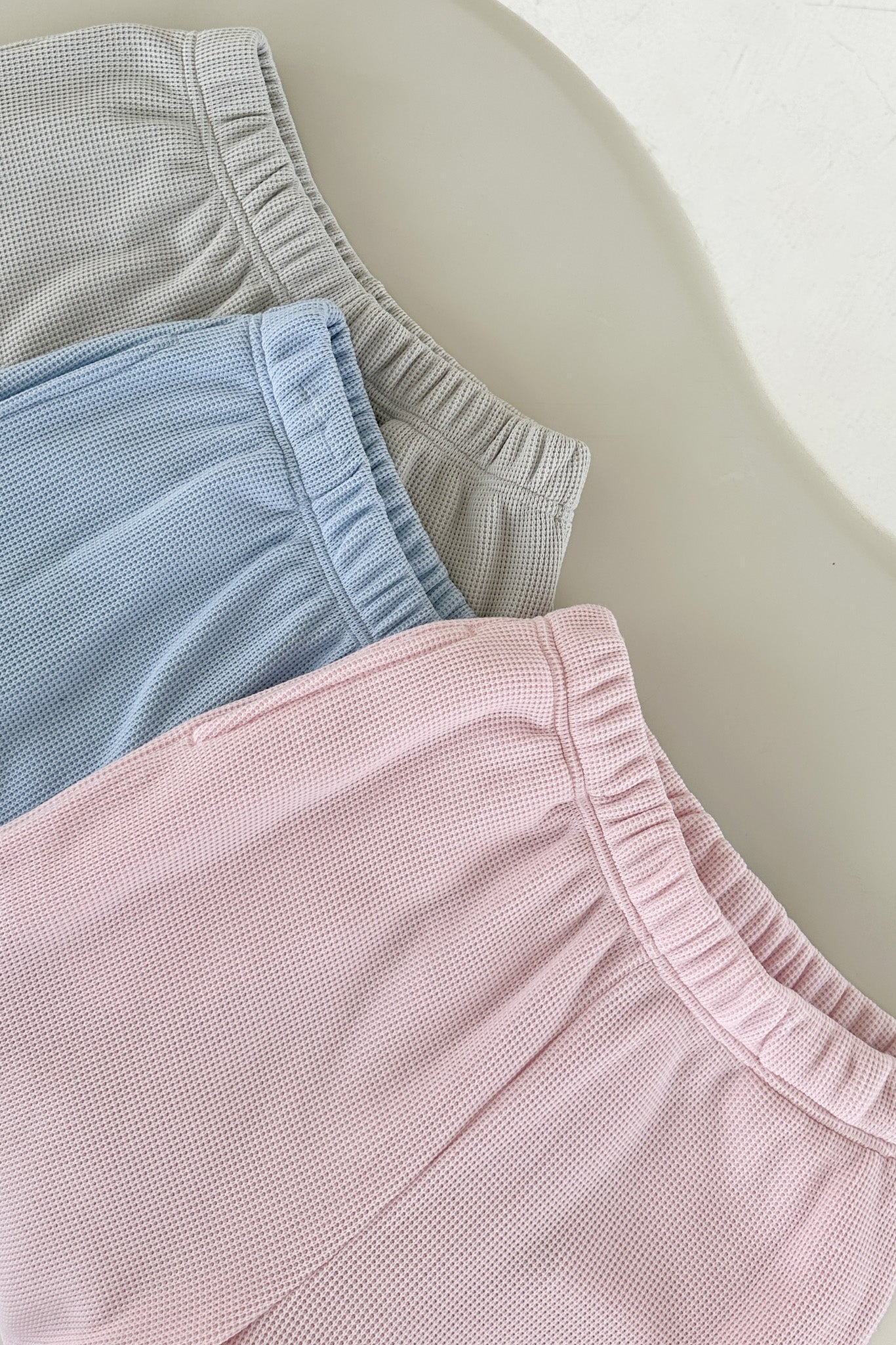 Close-up of pink, blue, and gray shorts on a light background