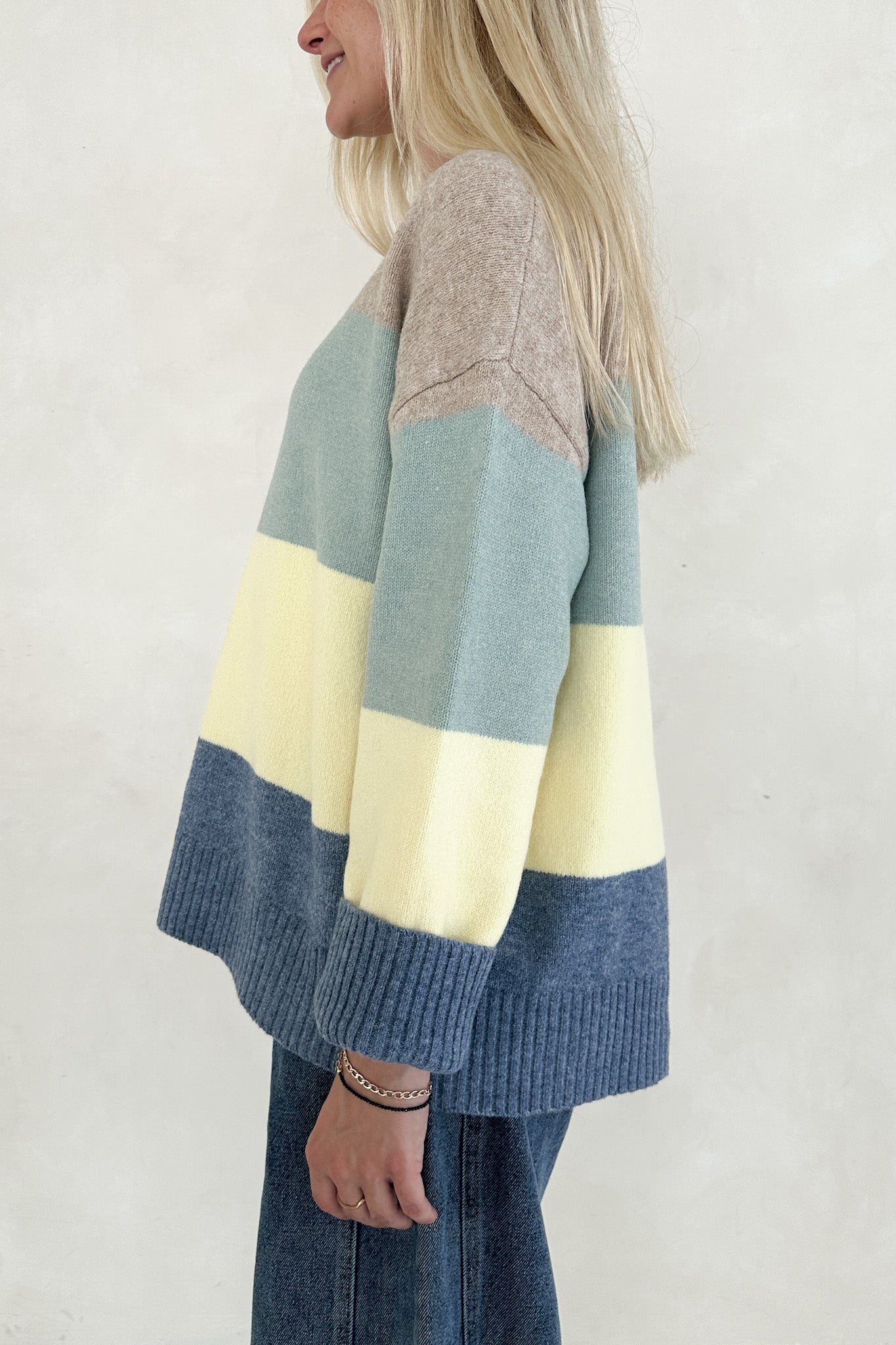 Person wearing a colorful striped sweater with a plain background