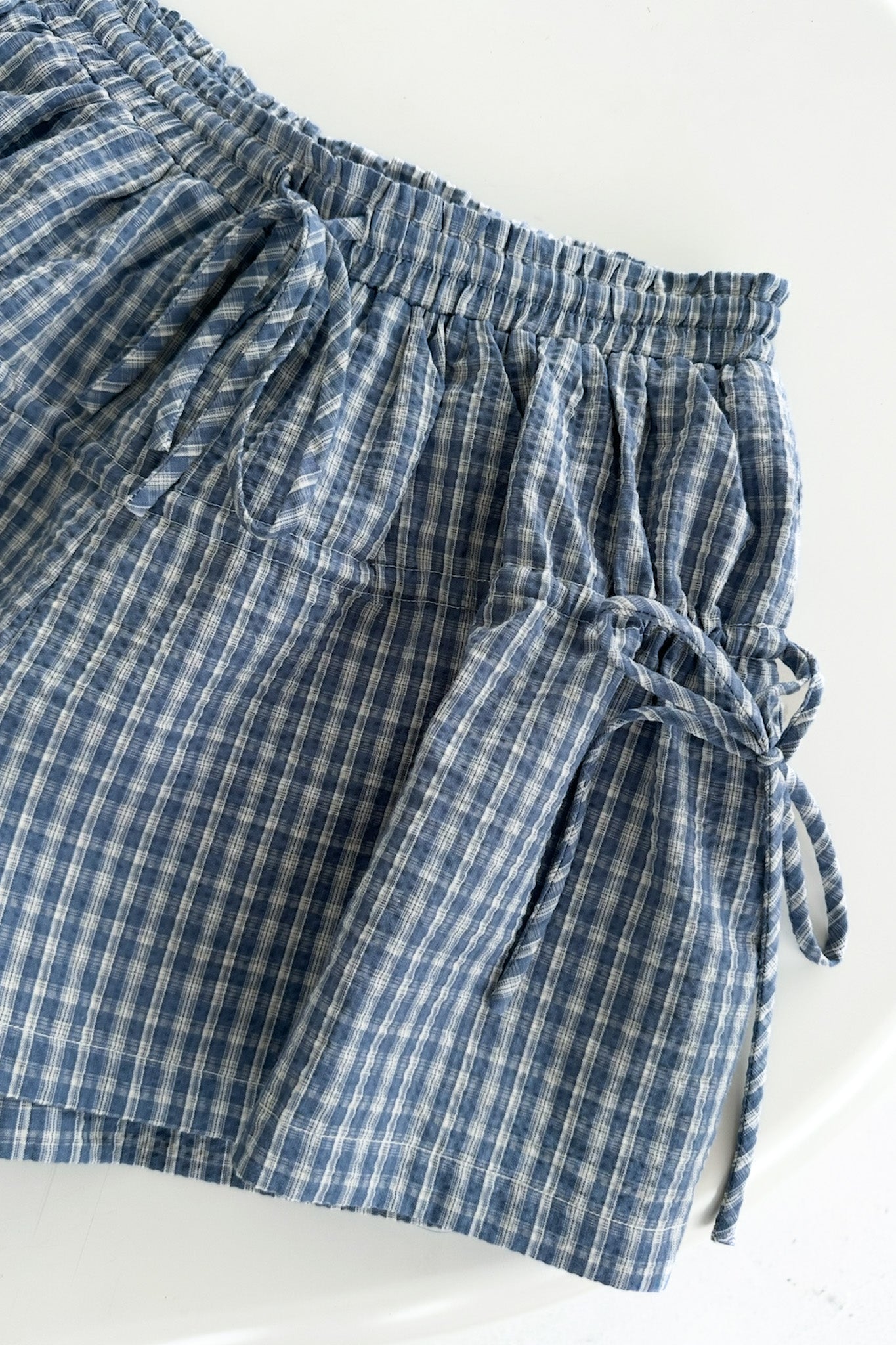 Blue and white checkered shorts with a tie waist on a white background