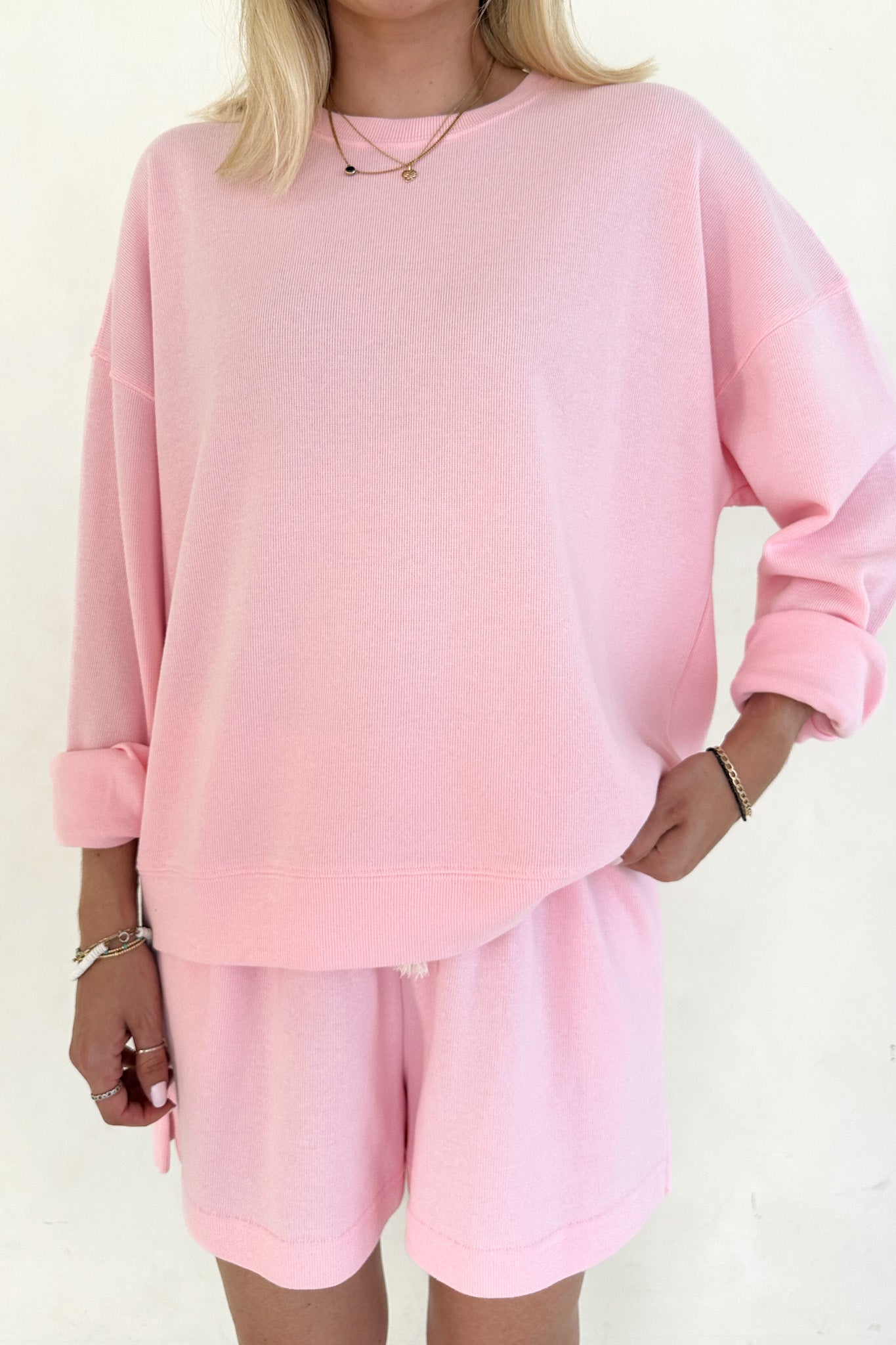 Person wearing a pink outfit with a matching top and shorts on a white background