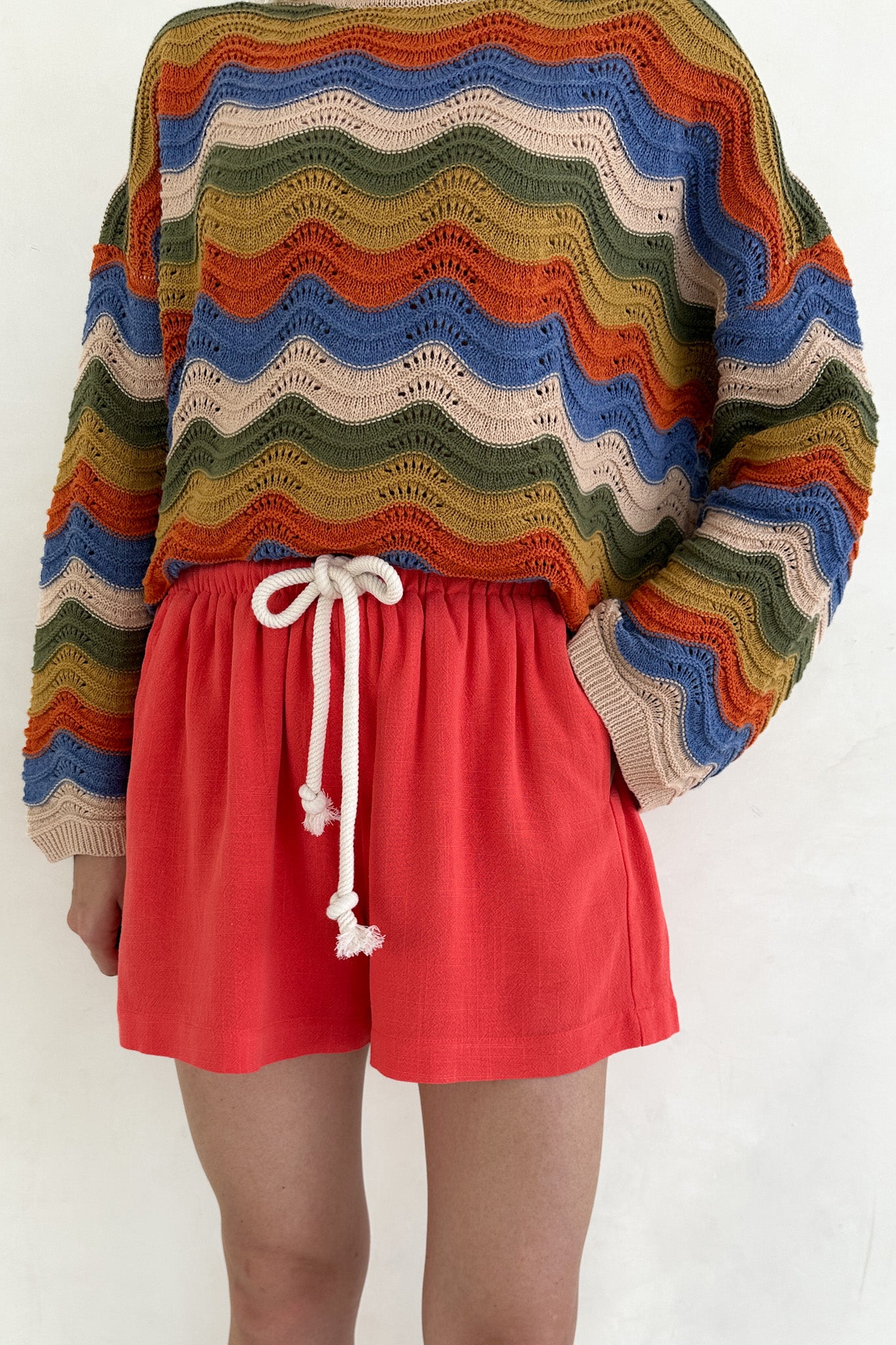 Colorful striped sweater with a person wearing red shorts on a white background