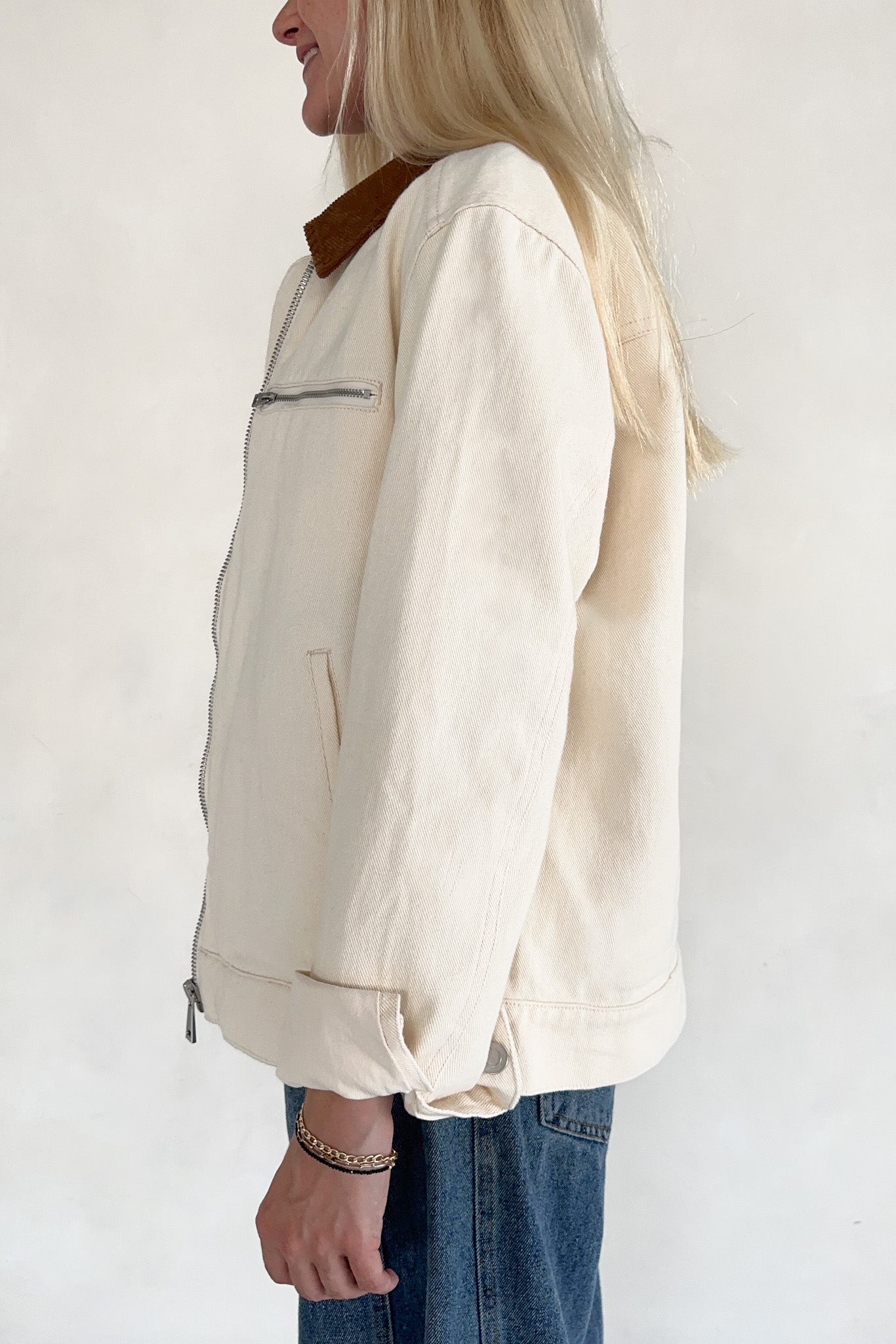 Person wearing a cream-colored jacket with a brown collar on a white background