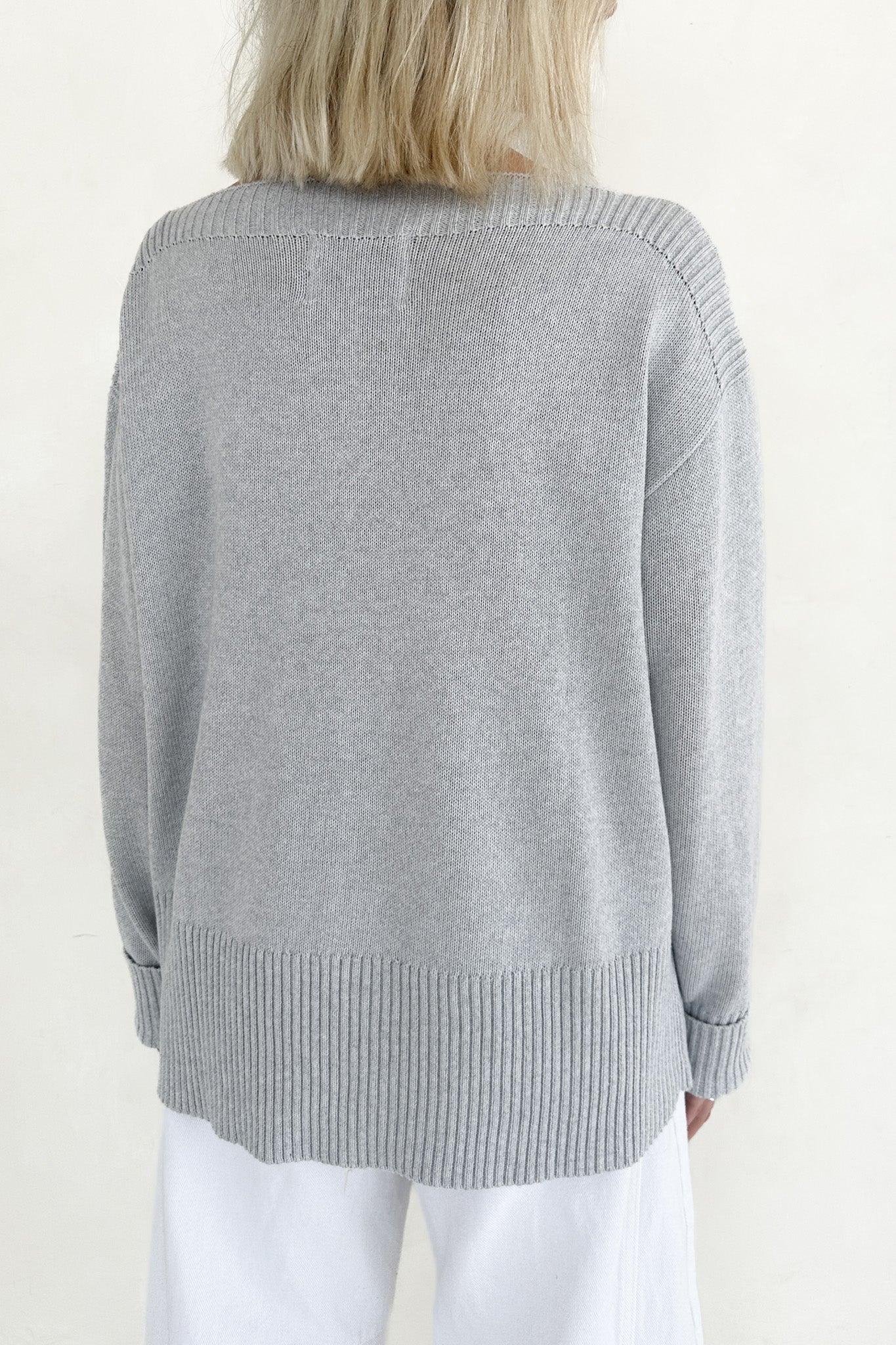 Gray sweater worn by a person on a plain background