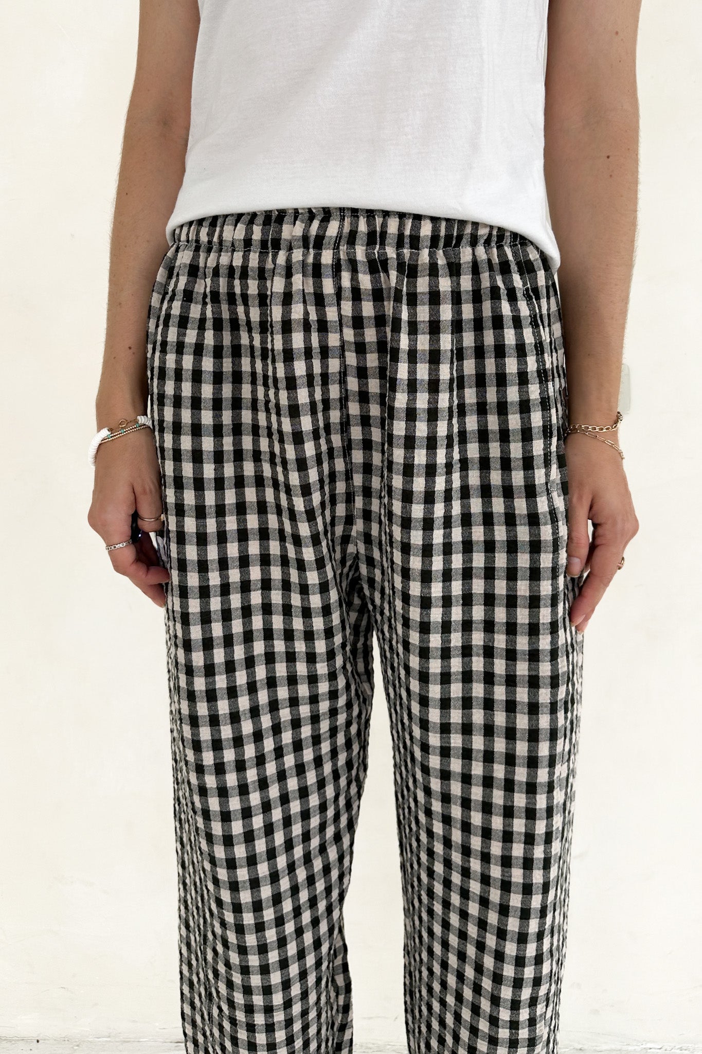 Person wearing black and white checkered pants with a plain background