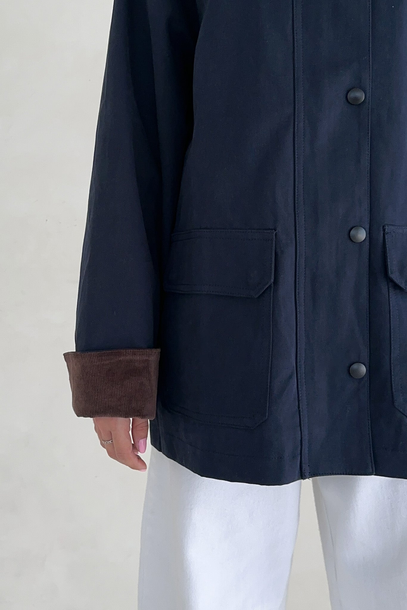 Navy blue coat with brown cuffs on a neutral background