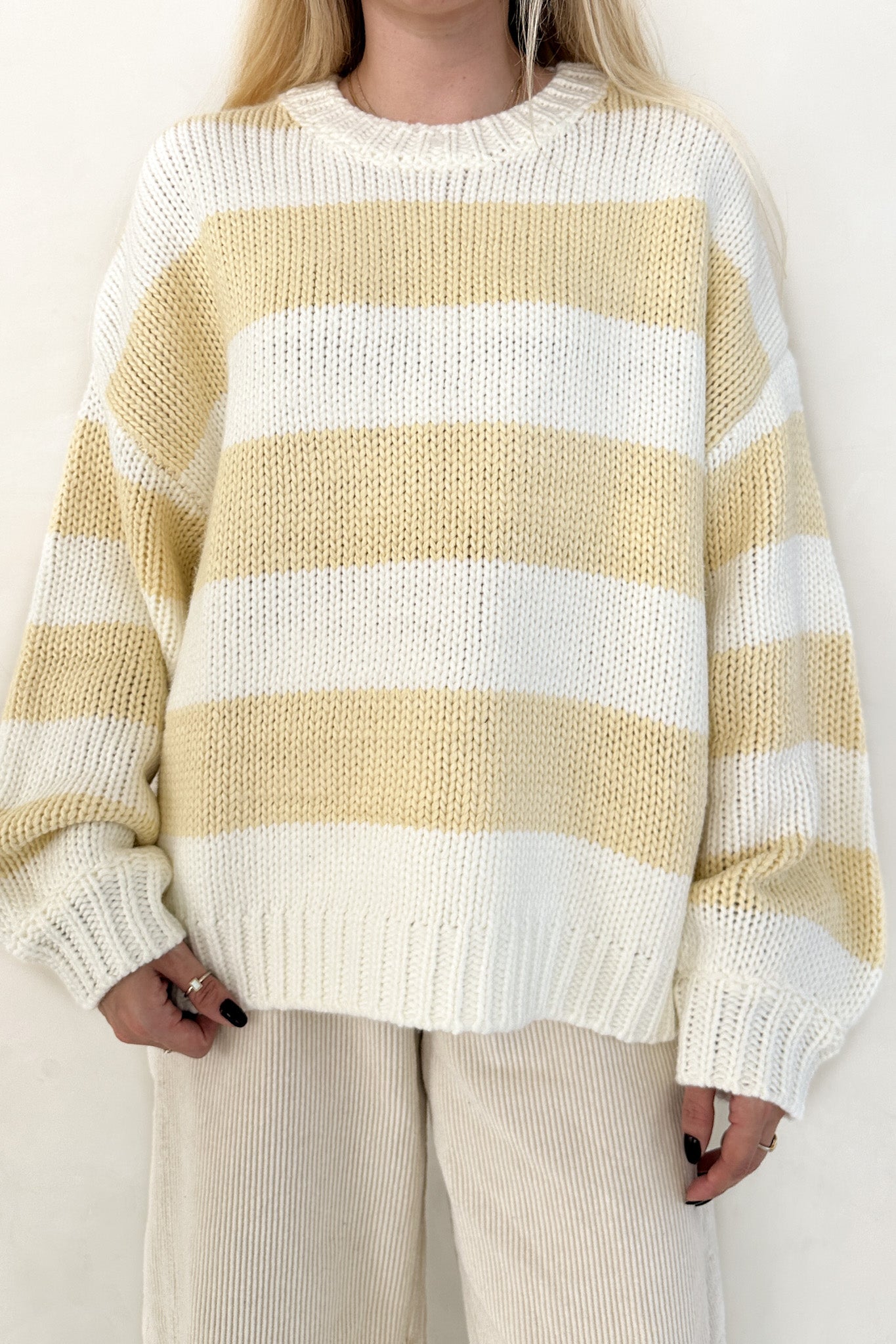 Person wearing a yellow and white striped sweater on a plain background