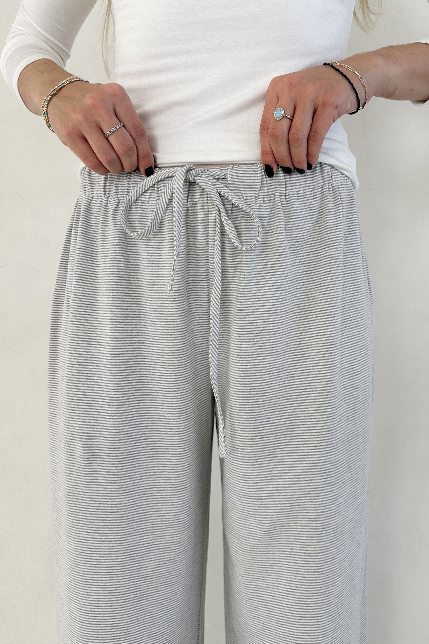 Person wearing gray striped pants with a white top against a plain background