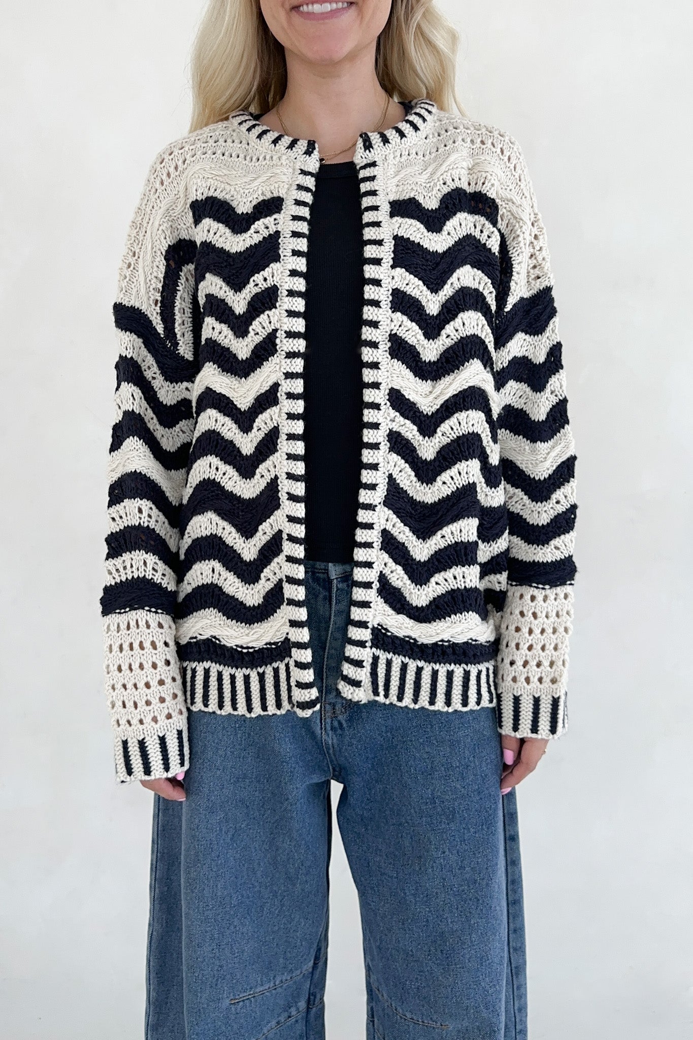 Person wearing a crocheted cardigan with a chevron pattern on a white background