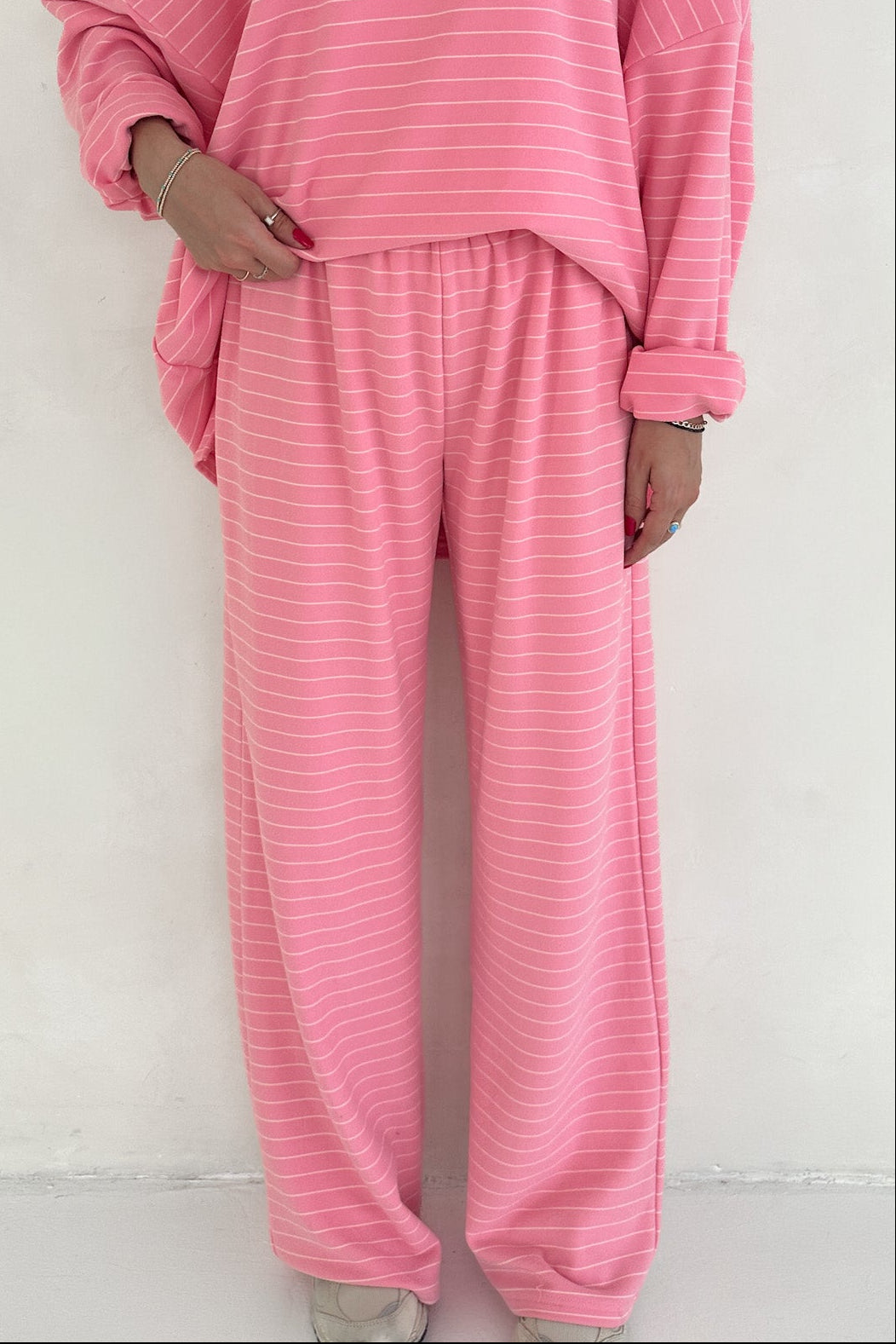 Person wearing a pink striped pajama set against a white background
