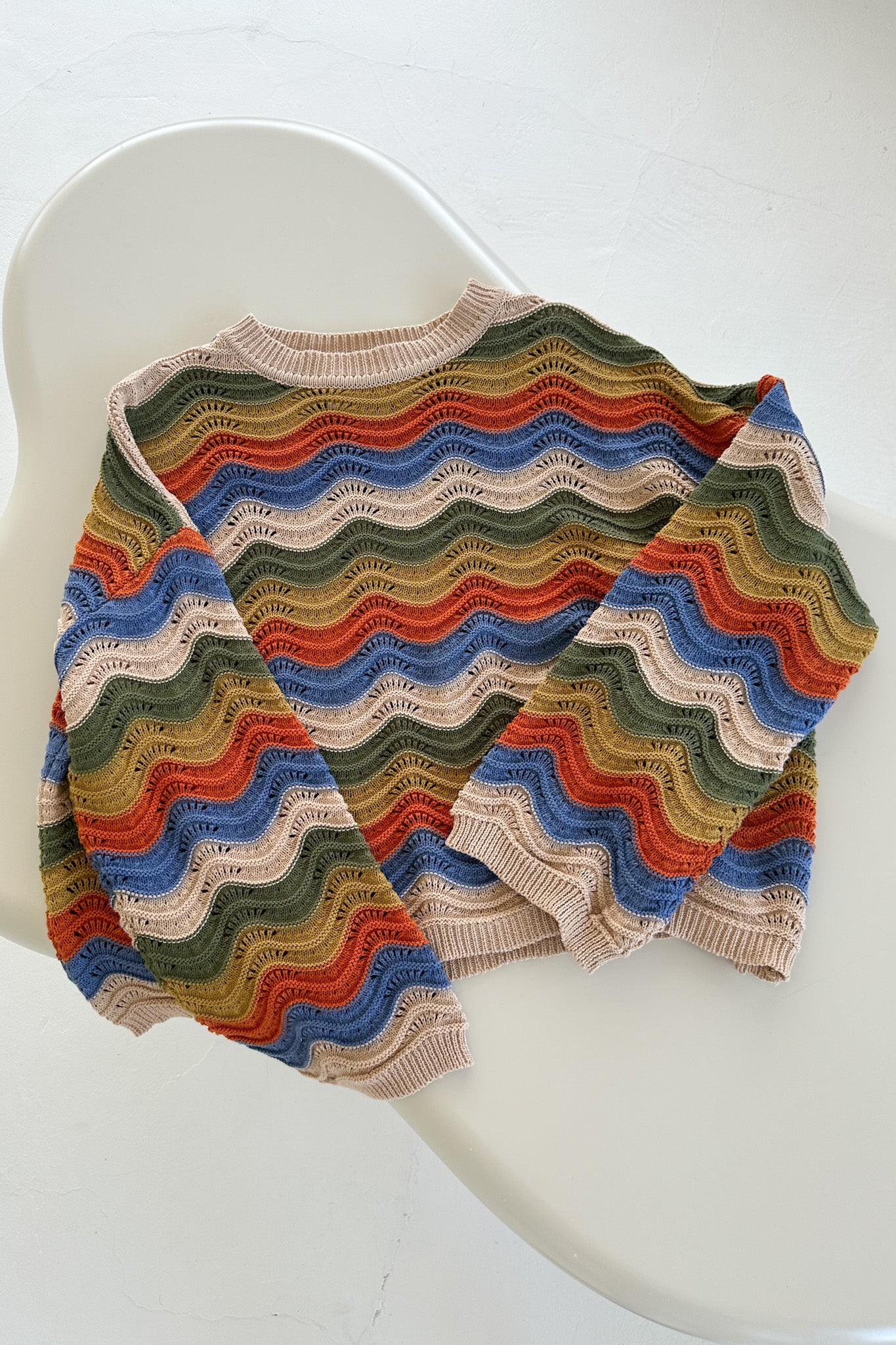 Colorful knitted shawl on a white chair