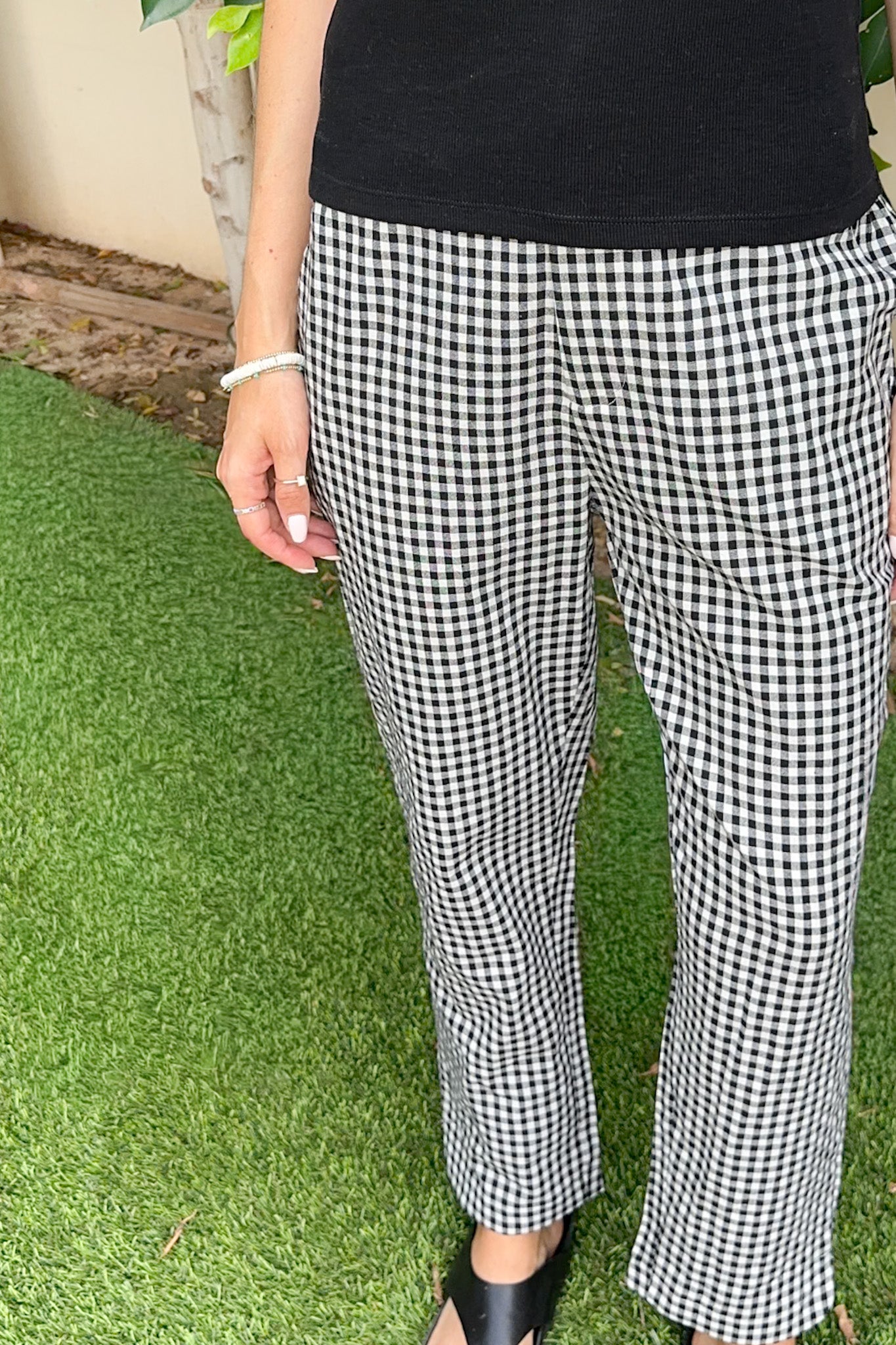 Person wearing black and white checkered pants on a grassy background