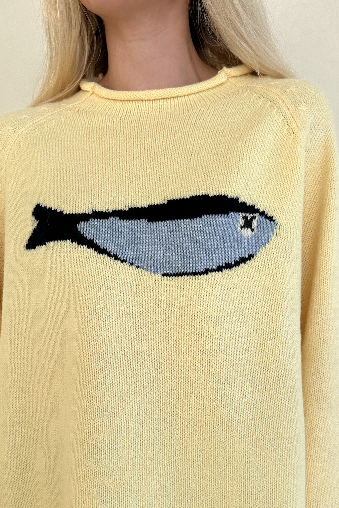 Yellow sweater with a fish design on a neutral background