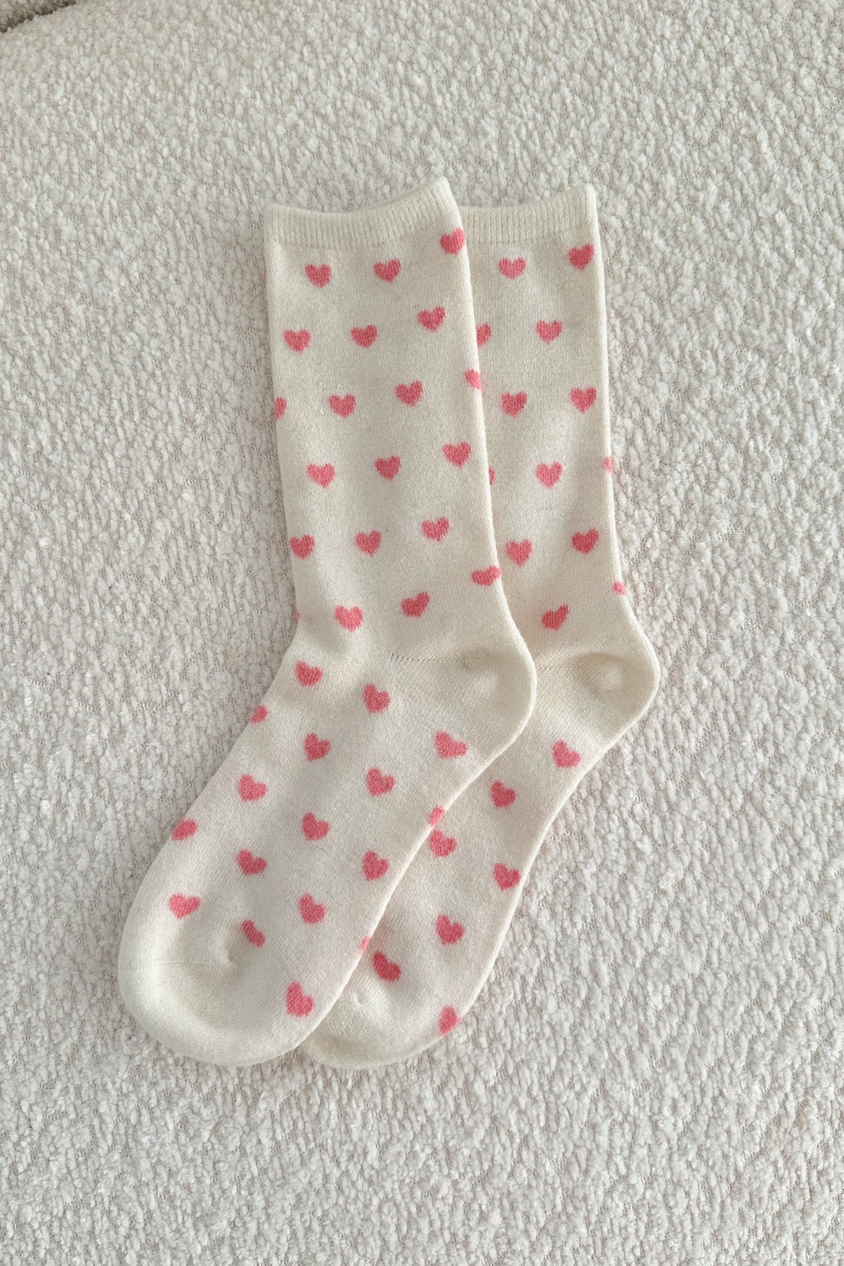 White socks with pink heart patterns on a light gray surface