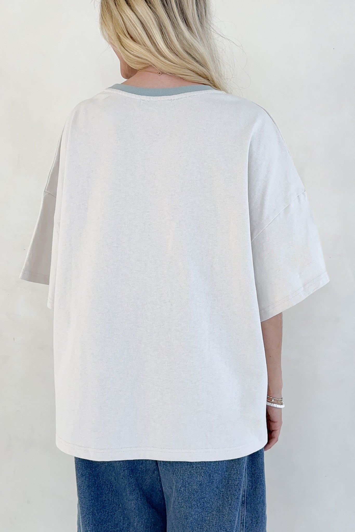 Person wearing a green button-up shirt with rolled-up sleeves against a white background