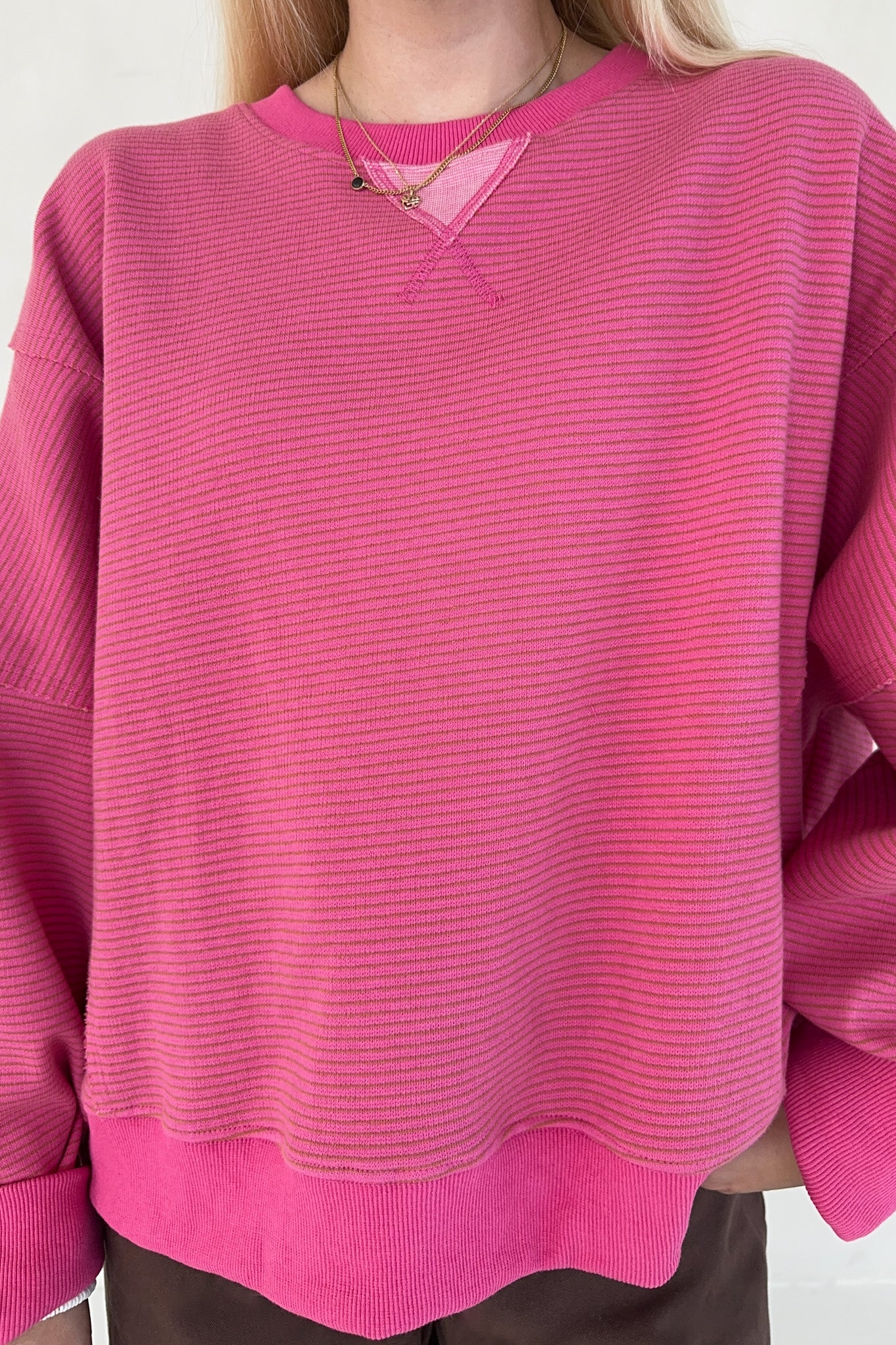 Pink sweater worn by a person on a white background