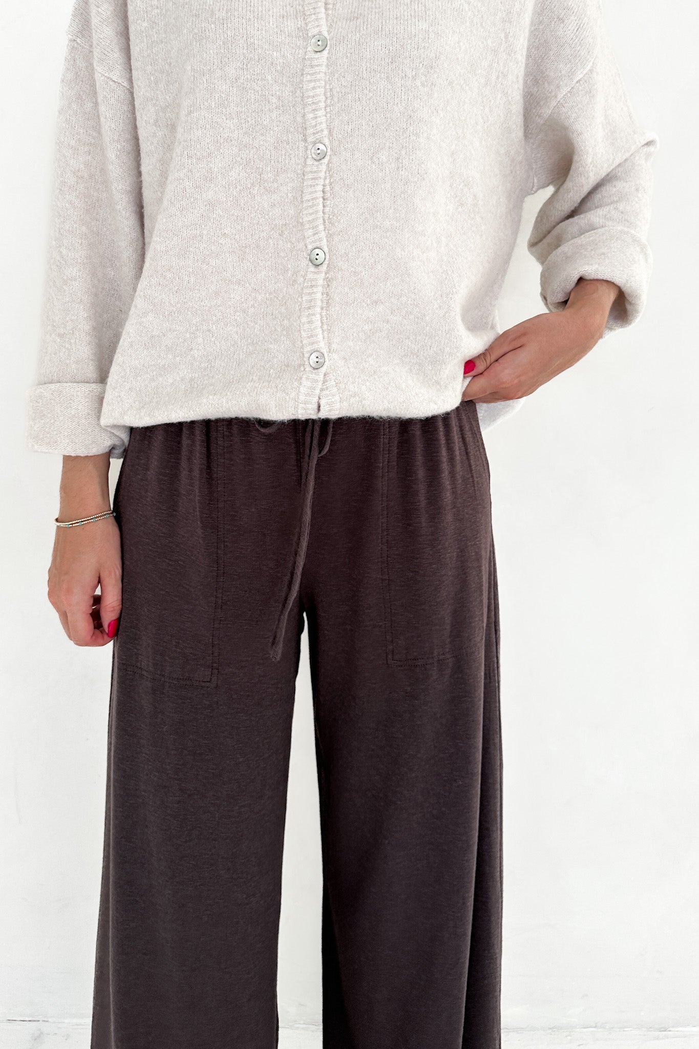 Person wearing a light gray sweater and brown pants on a white background