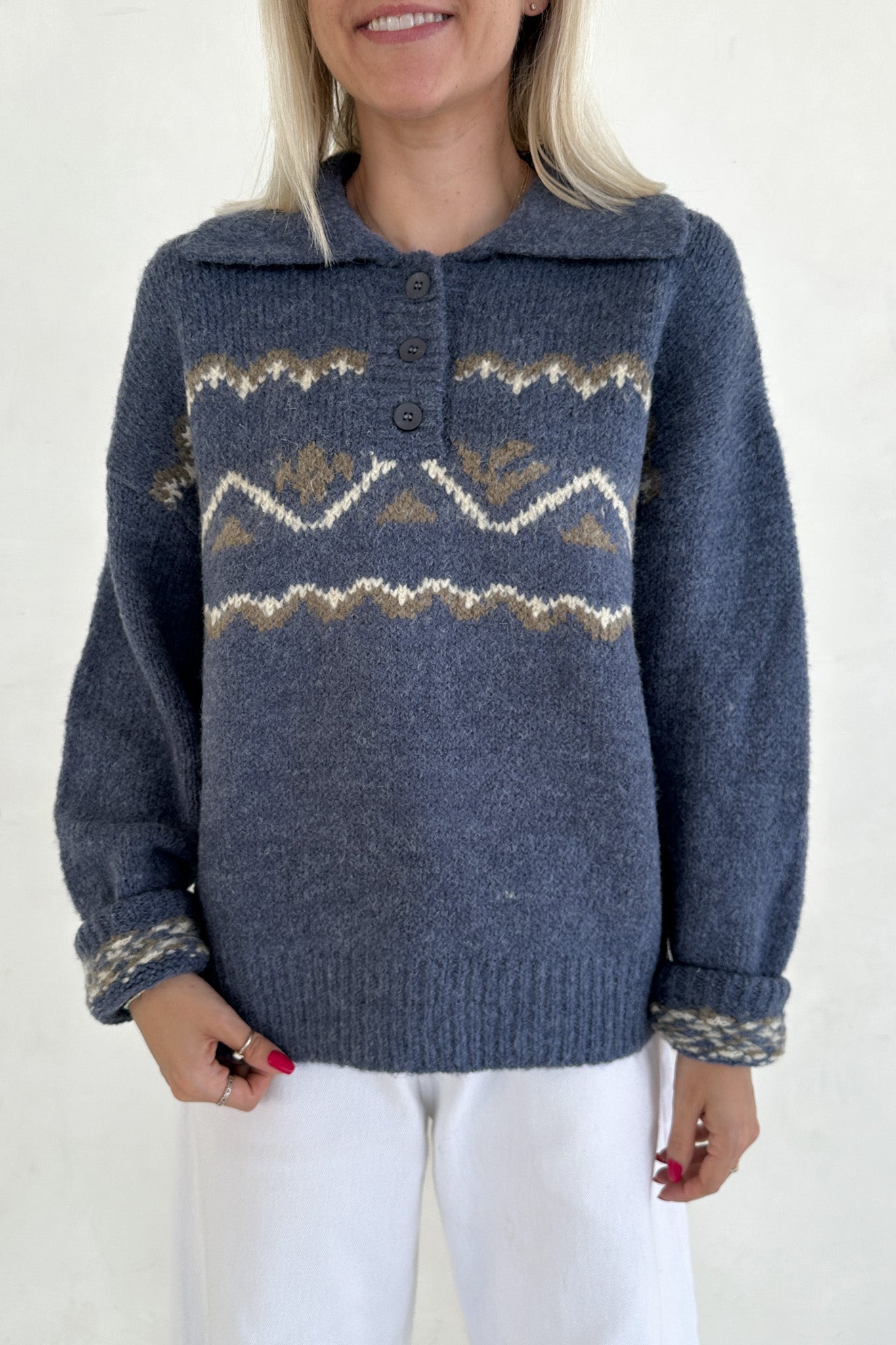 Woman wearing a blue knitted sweater with a patterned design on a white background