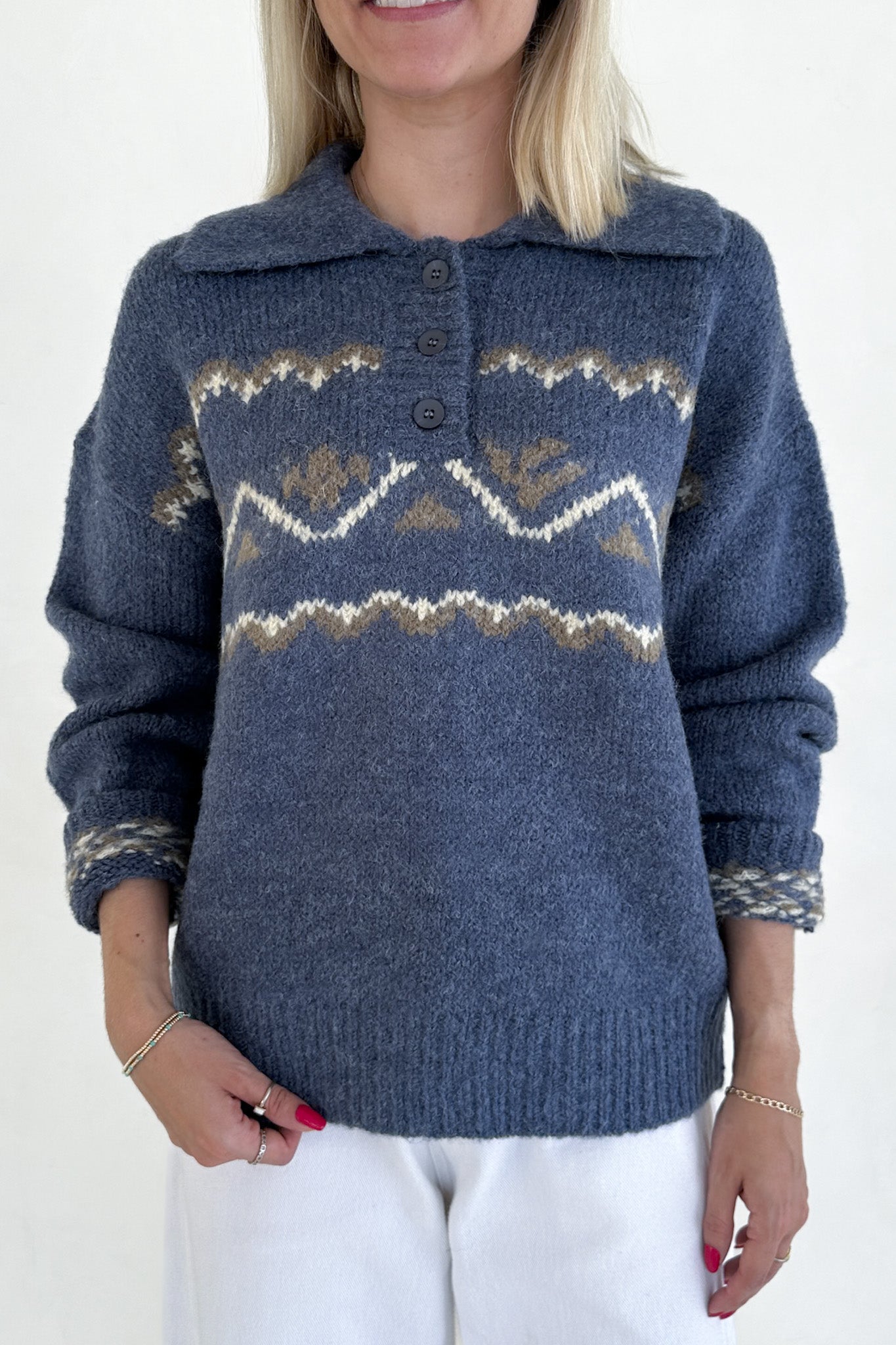 Person wearing a blue knitted sweater with patterned design on a white background