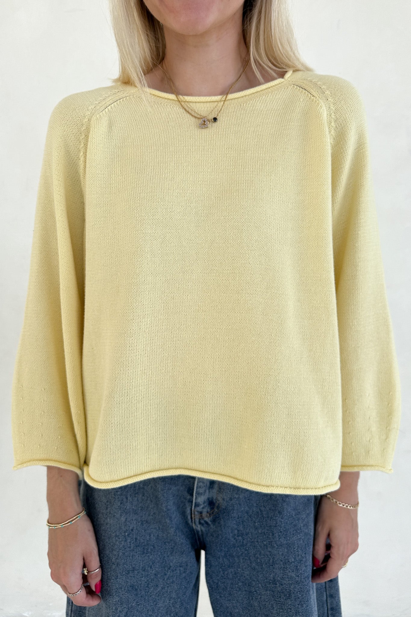 Person wearing a yellow sweater and blue jeans on a white background