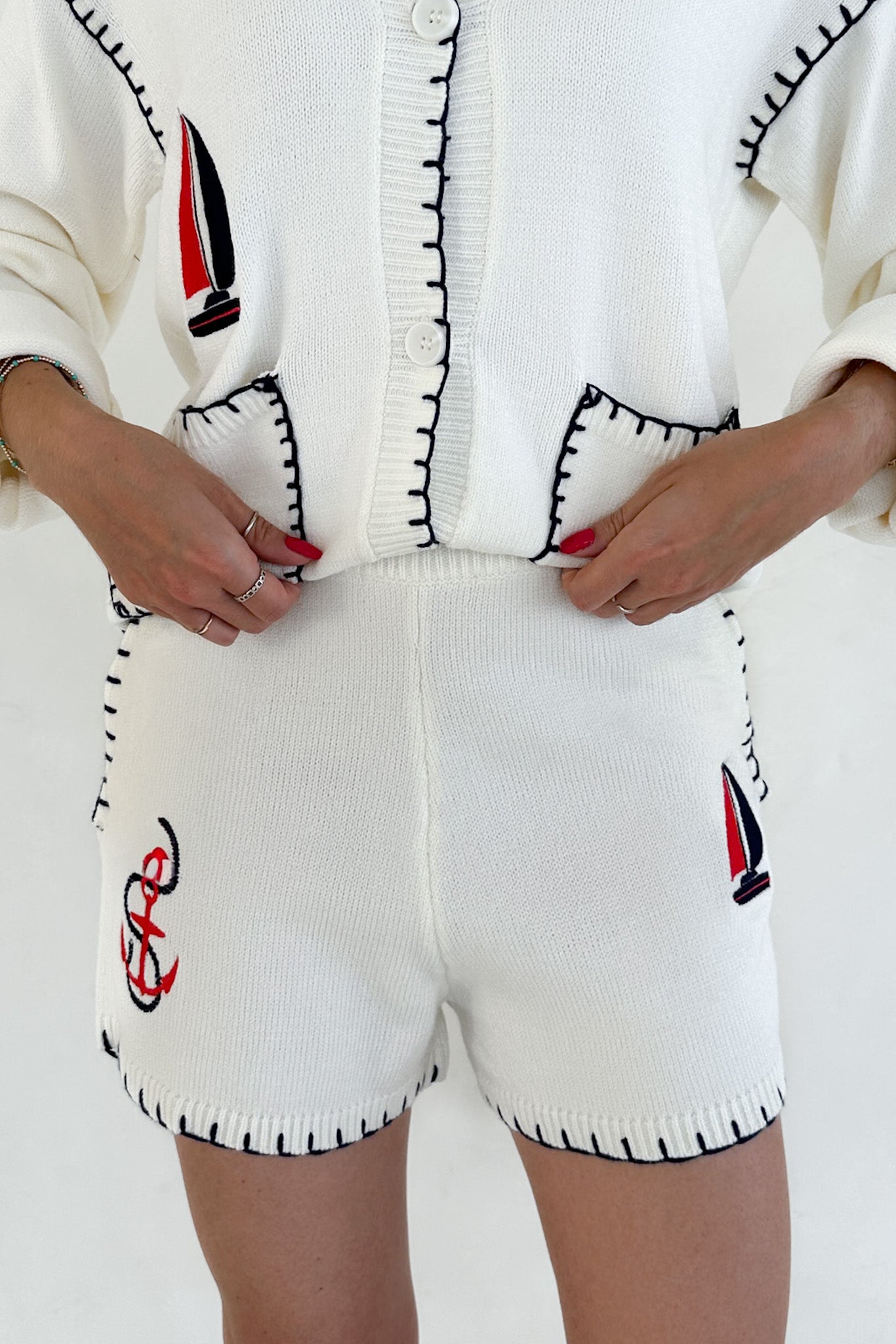 White knitted outfit with black and red accents on a plain background