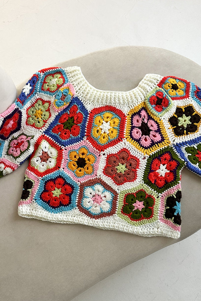 Colorful crochet hexagon-patterned sweater on a gray surface
