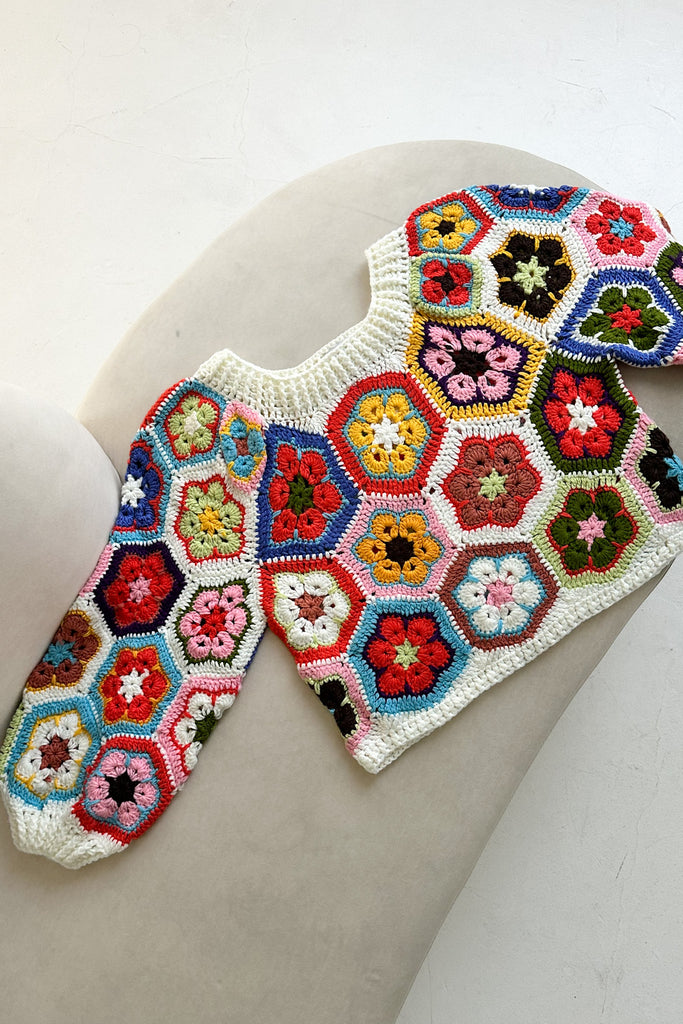Colorful crocheted hexagon-patterned garment on a white surface