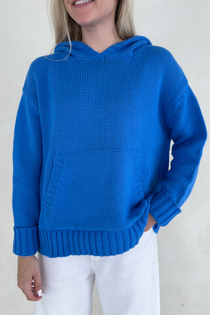 Person wearing a blue knitted hoodie against a plain background