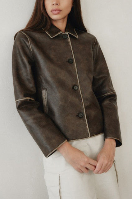 Woman wearing a brown leather jacket against a white background