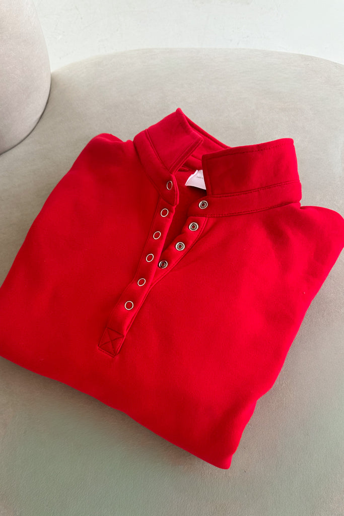 Folded red polo shirt on a light surface