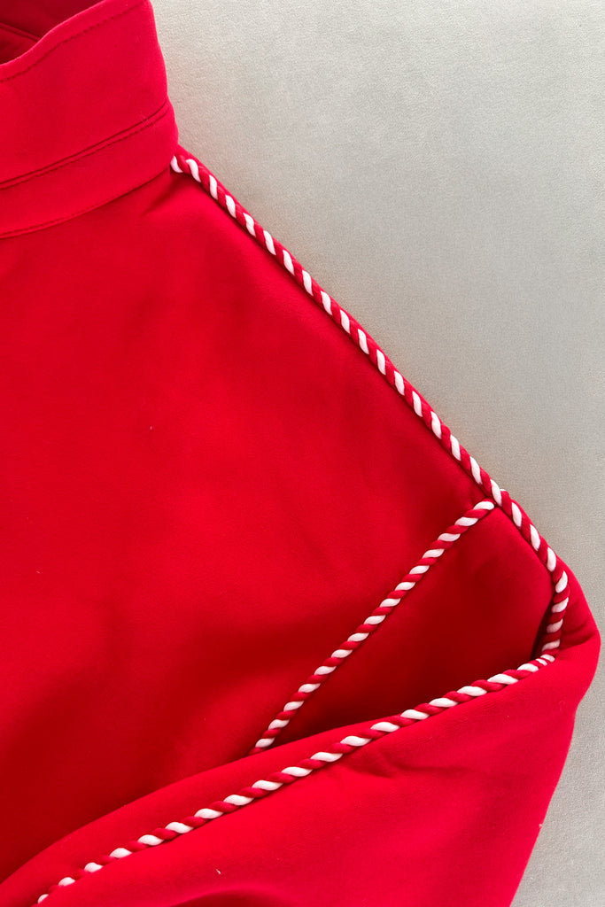 Close-up of a red garment with white stitching on a neutral background