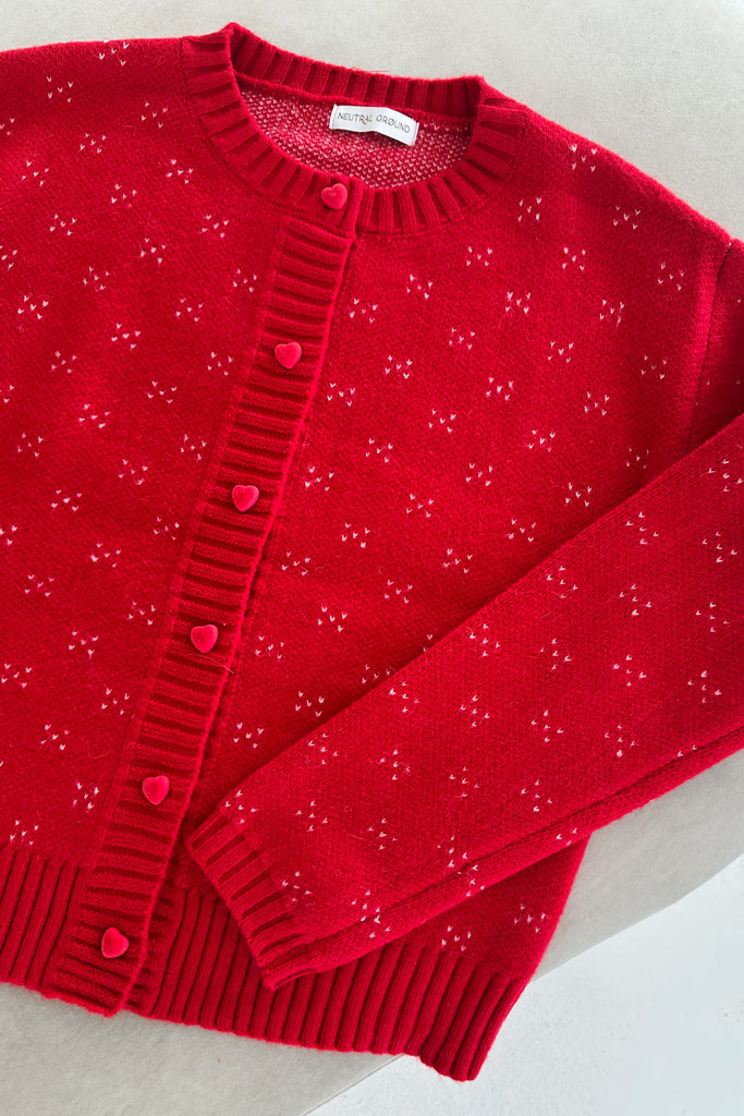 Red cardigan with heart patterns on a light gray background