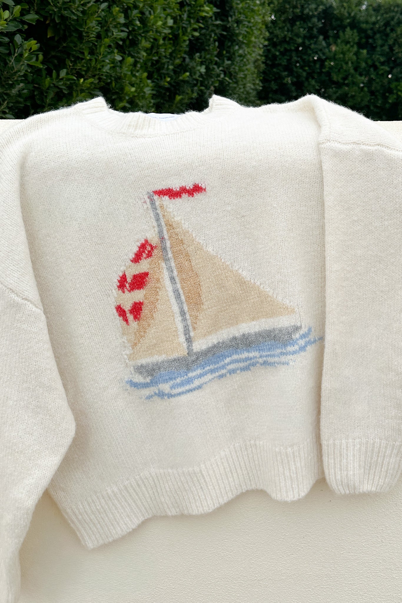 White sweater with a sailboat design on a white background