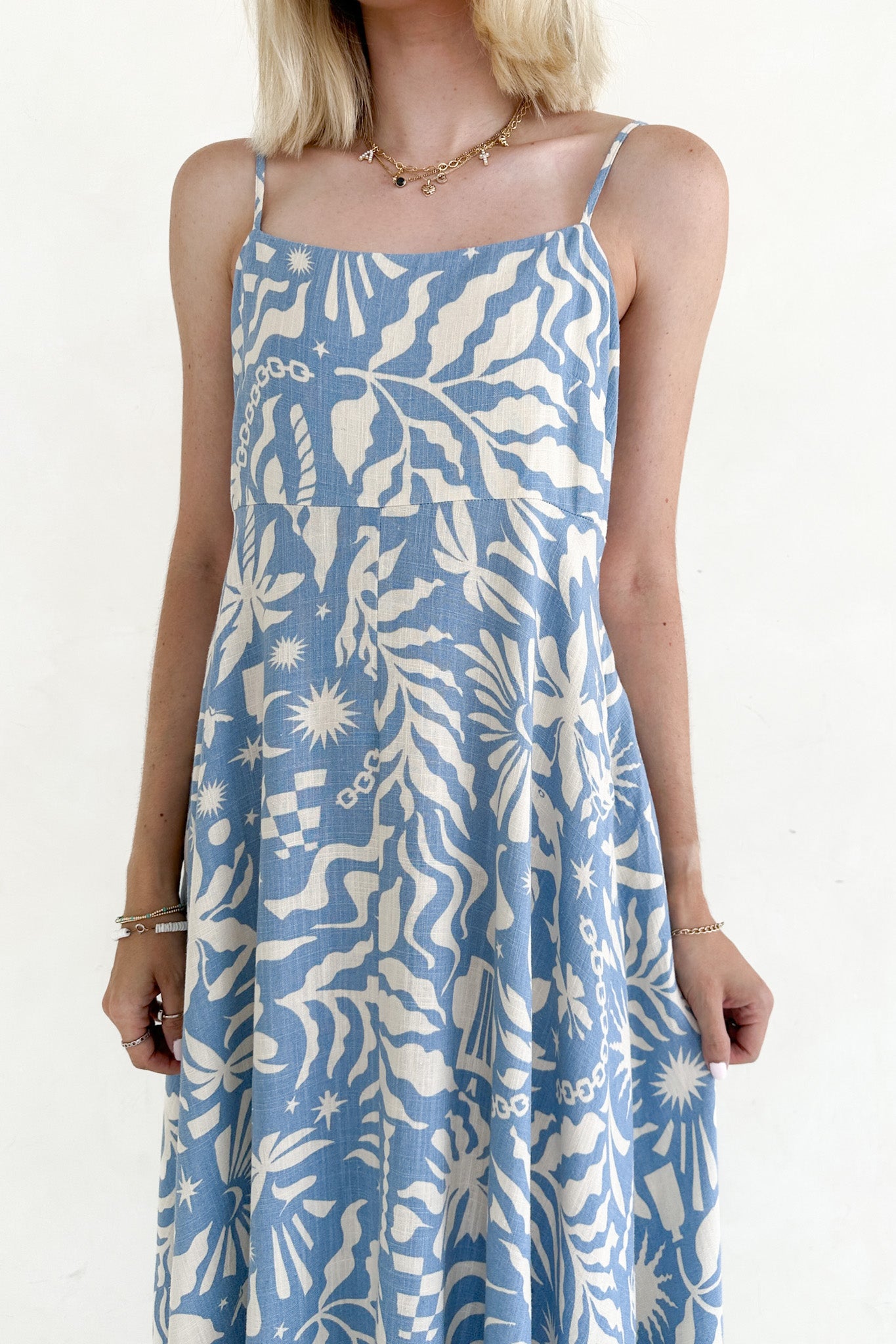Woman wearing a blue and white patterned dress against a plain background