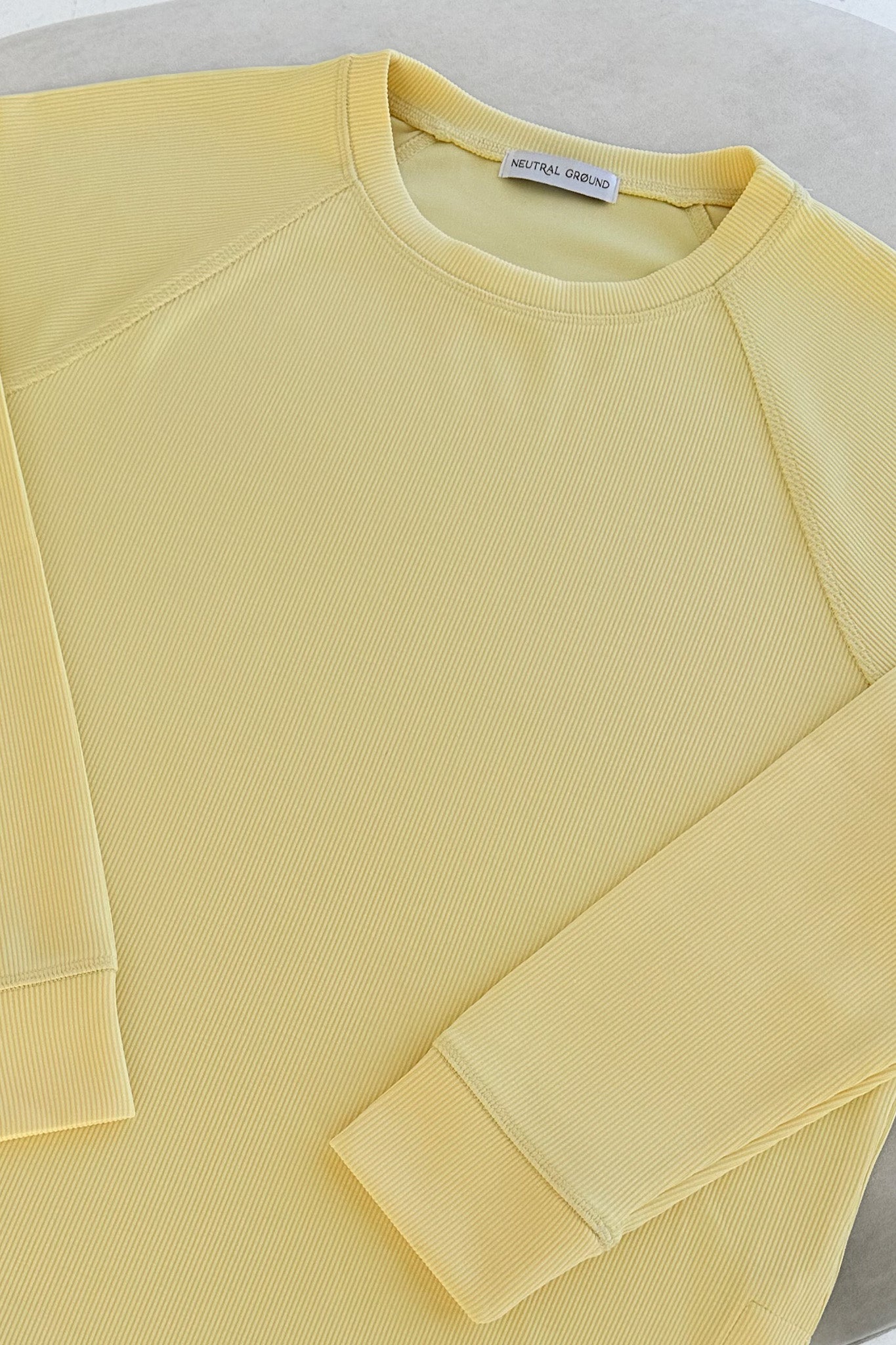 Yellow sweatshirt with a brand label on a light background