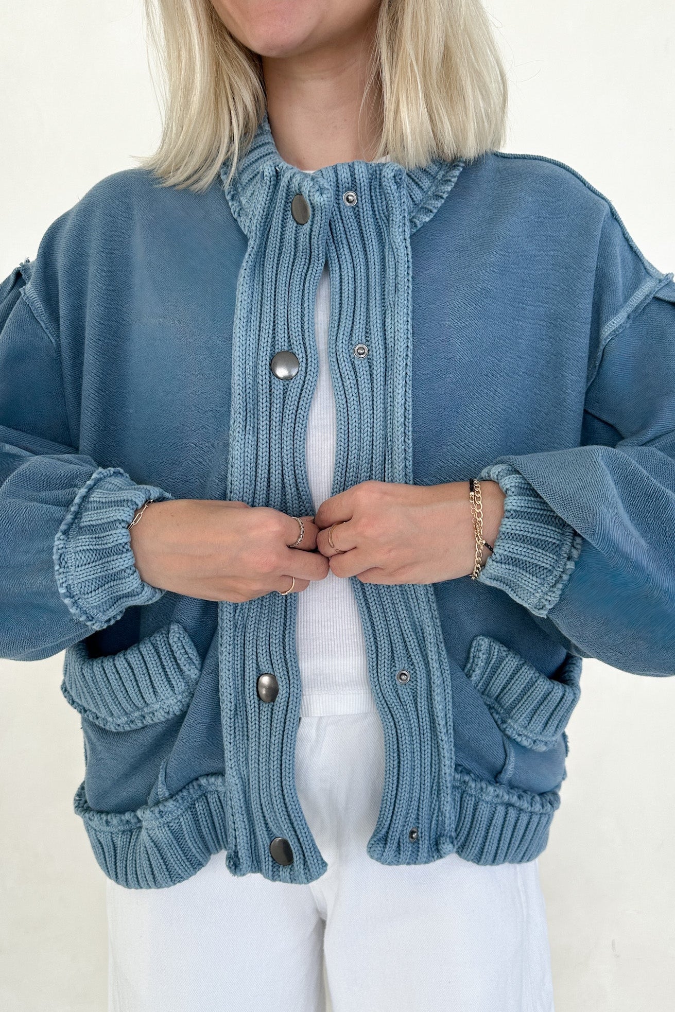 Woman wearing a blue knitted cardigan with a plain background