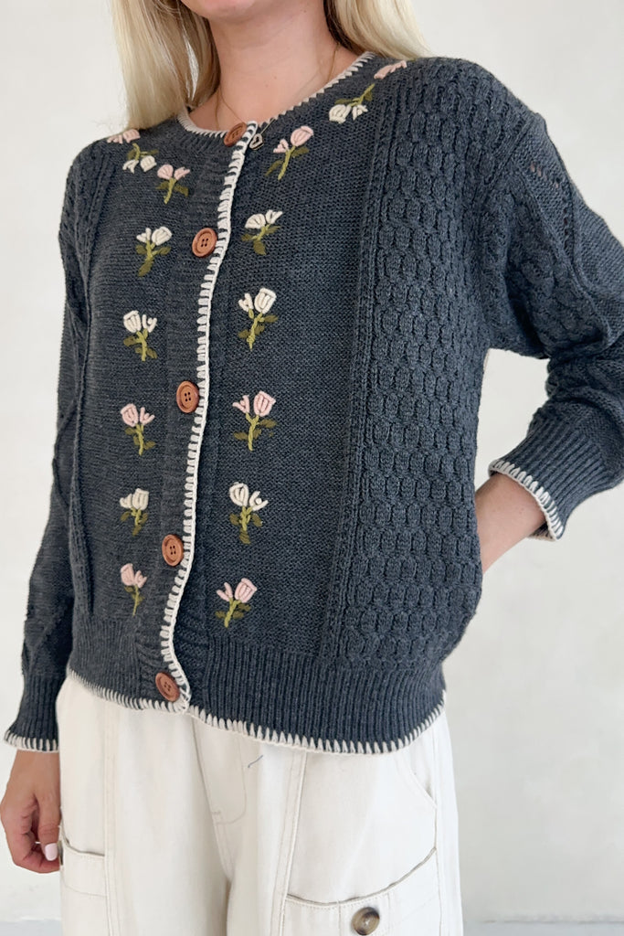 Dark blue knitted cardigan with floral embroidery on a plain background