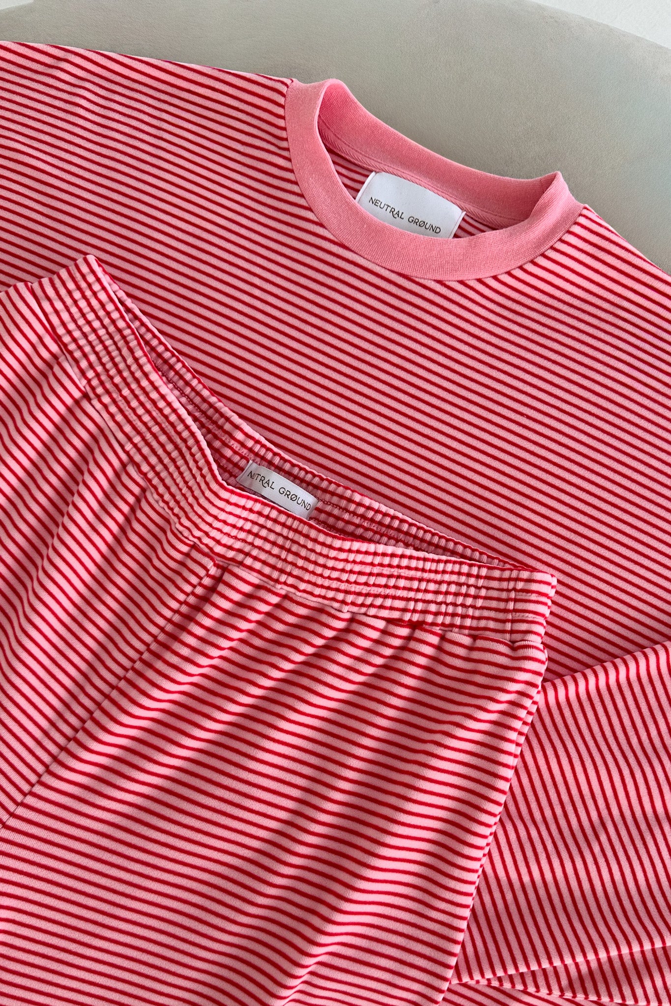 Pink striped shirt with a brand label on a light gray background