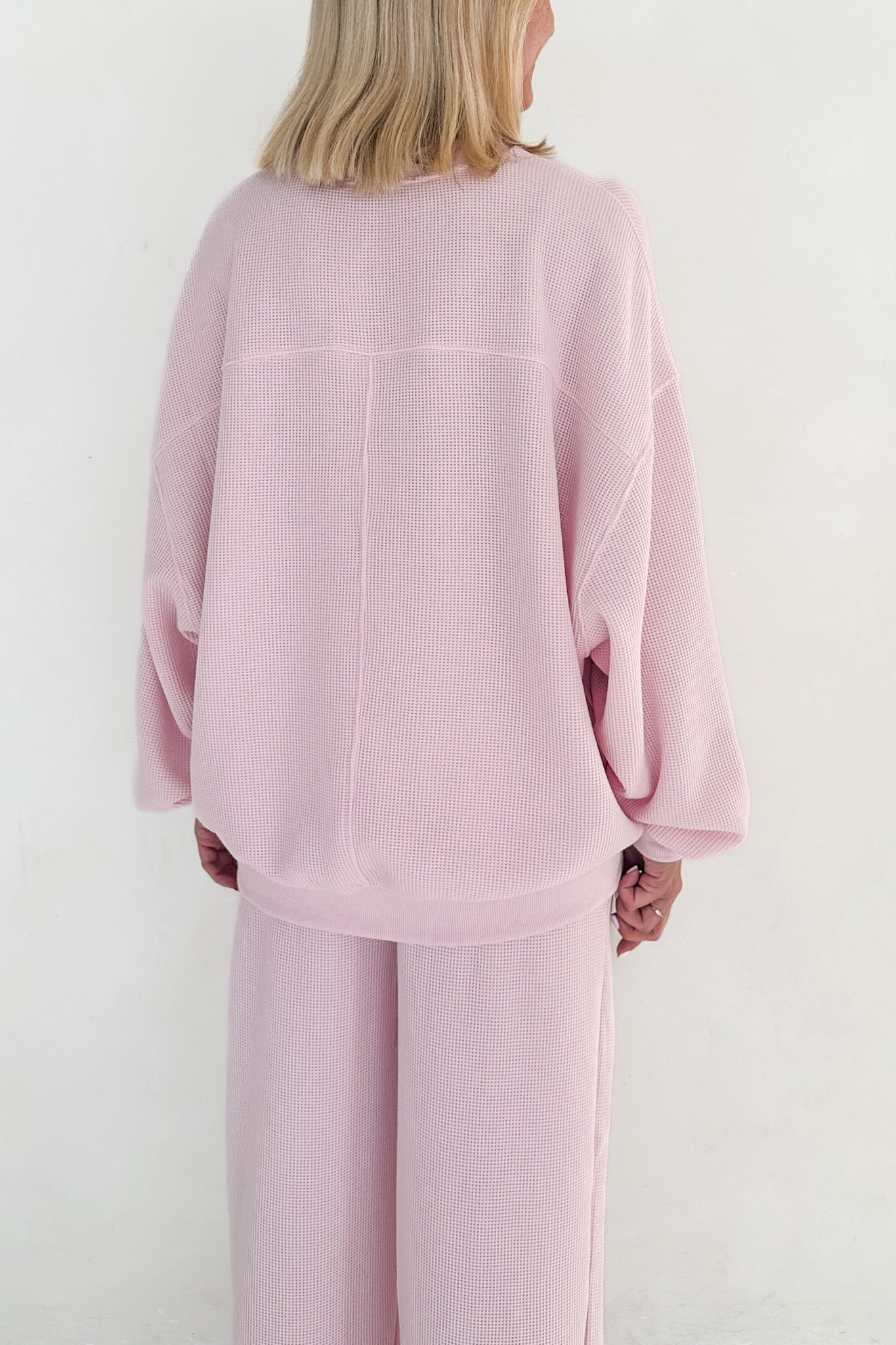 Person wearing a pink outfit against a white background