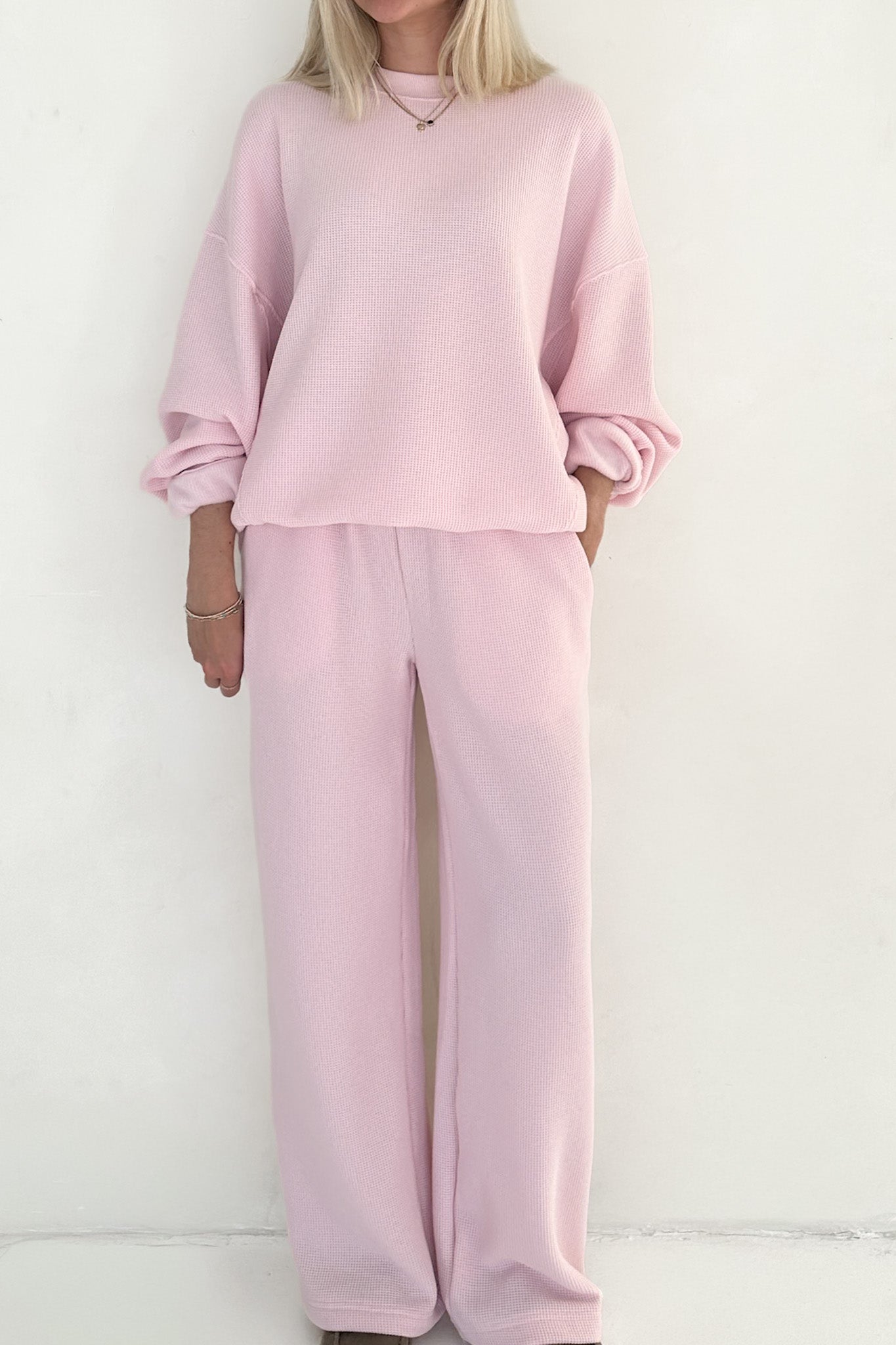 Person wearing a pink outfit with a matching top and pants on a white background